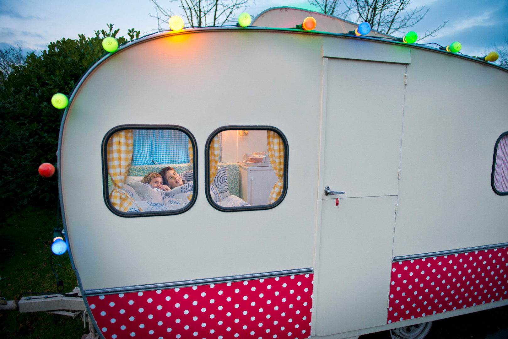 Wohnwagen, durch dessen Fenster zwei Kinder zu erkennen sind, die im Bett liegen