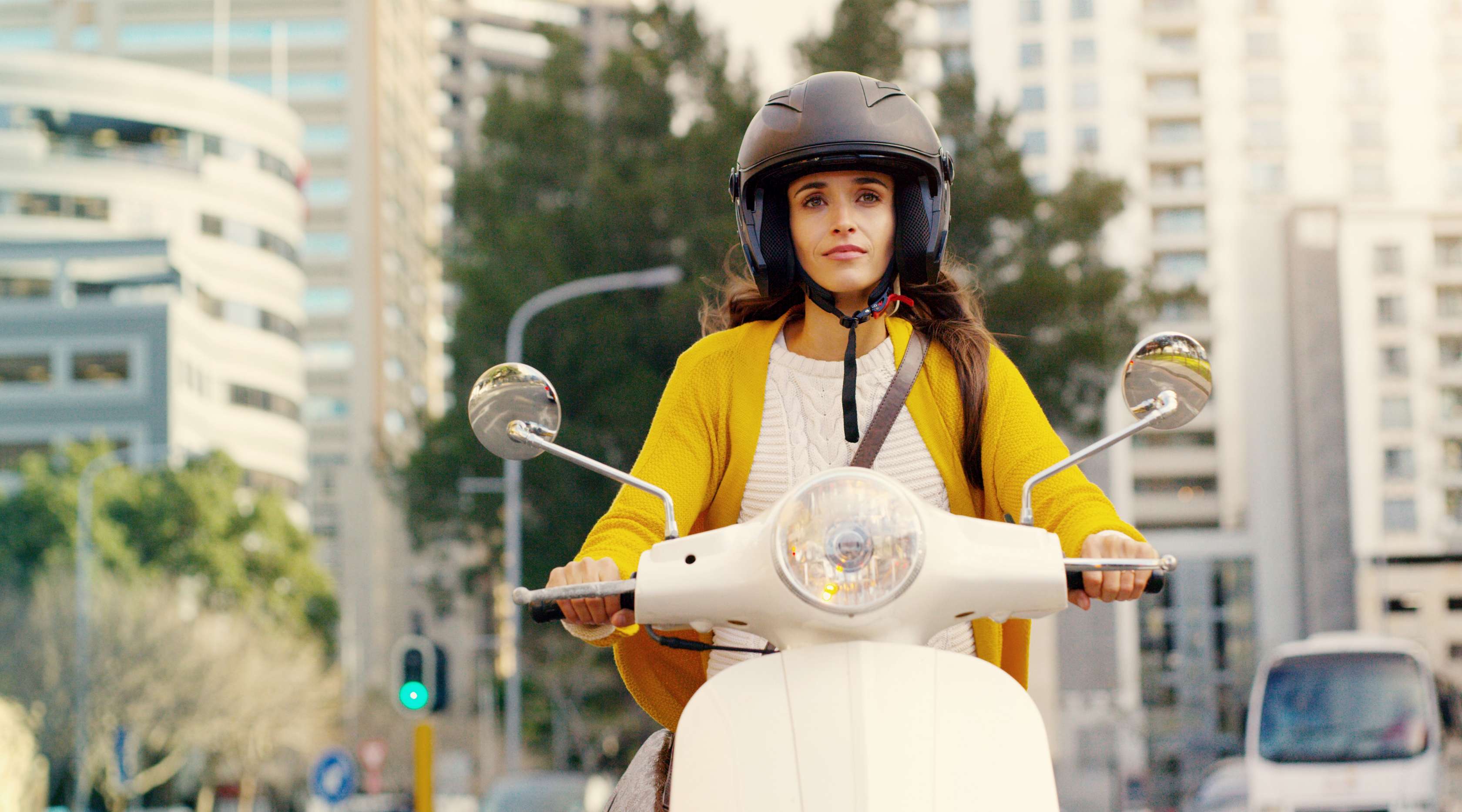 Allianz - Mopedversicherung: Frau auf Moped fährt durch die Stadt