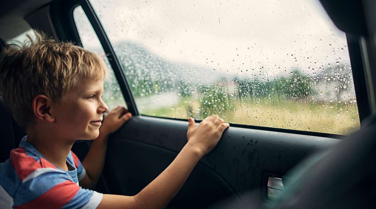 Allianz - Teilkasko: Junge im Auto bei Regen.