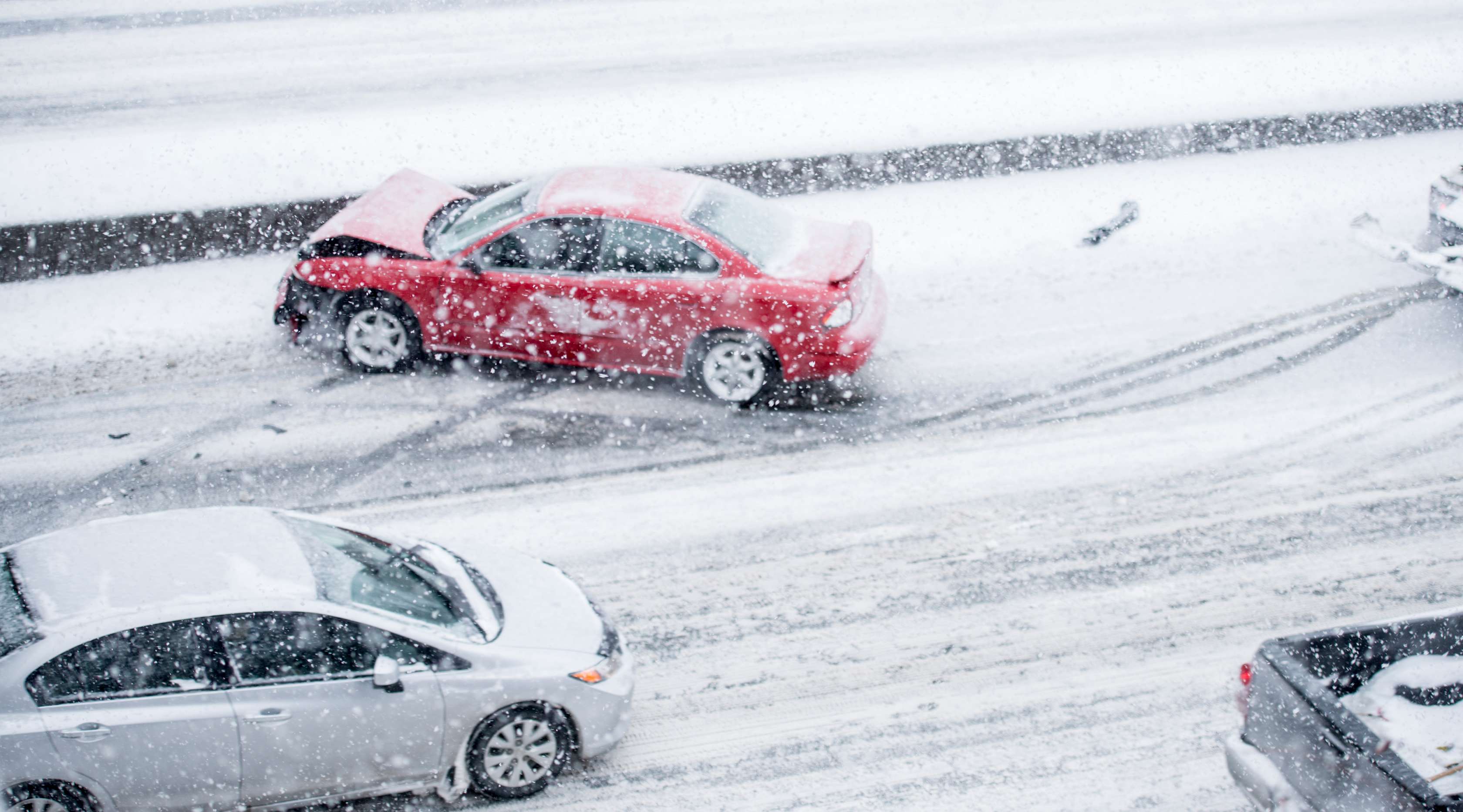 Allianz - Kfz-Versicherung Allwetterreifen: Roter und silberner Pkw stehen nach Autounfall beschädigt auf schneebedeckter Straße