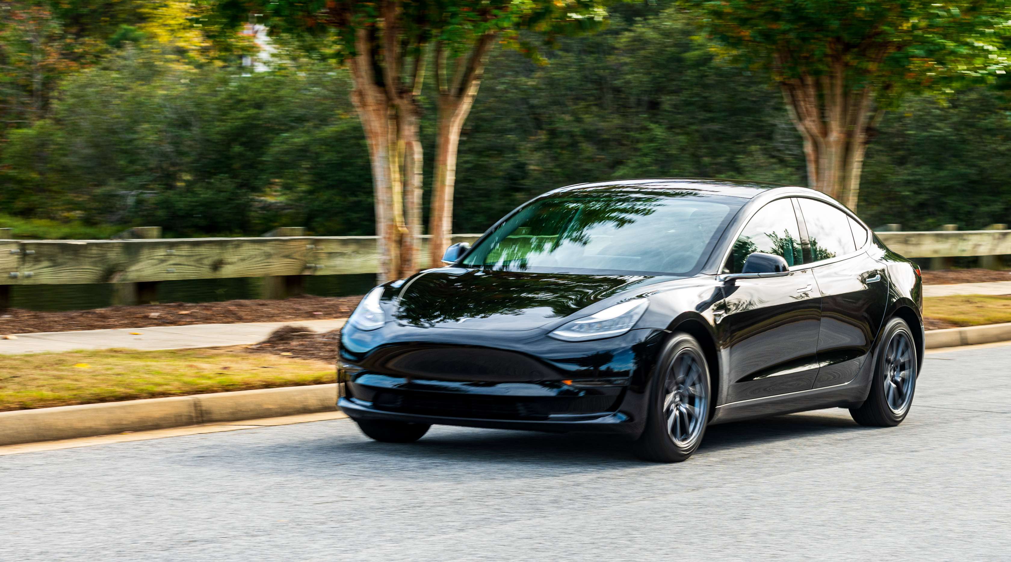 Schwarzer Tesla fährt auf einer Straße, Frontalansicht