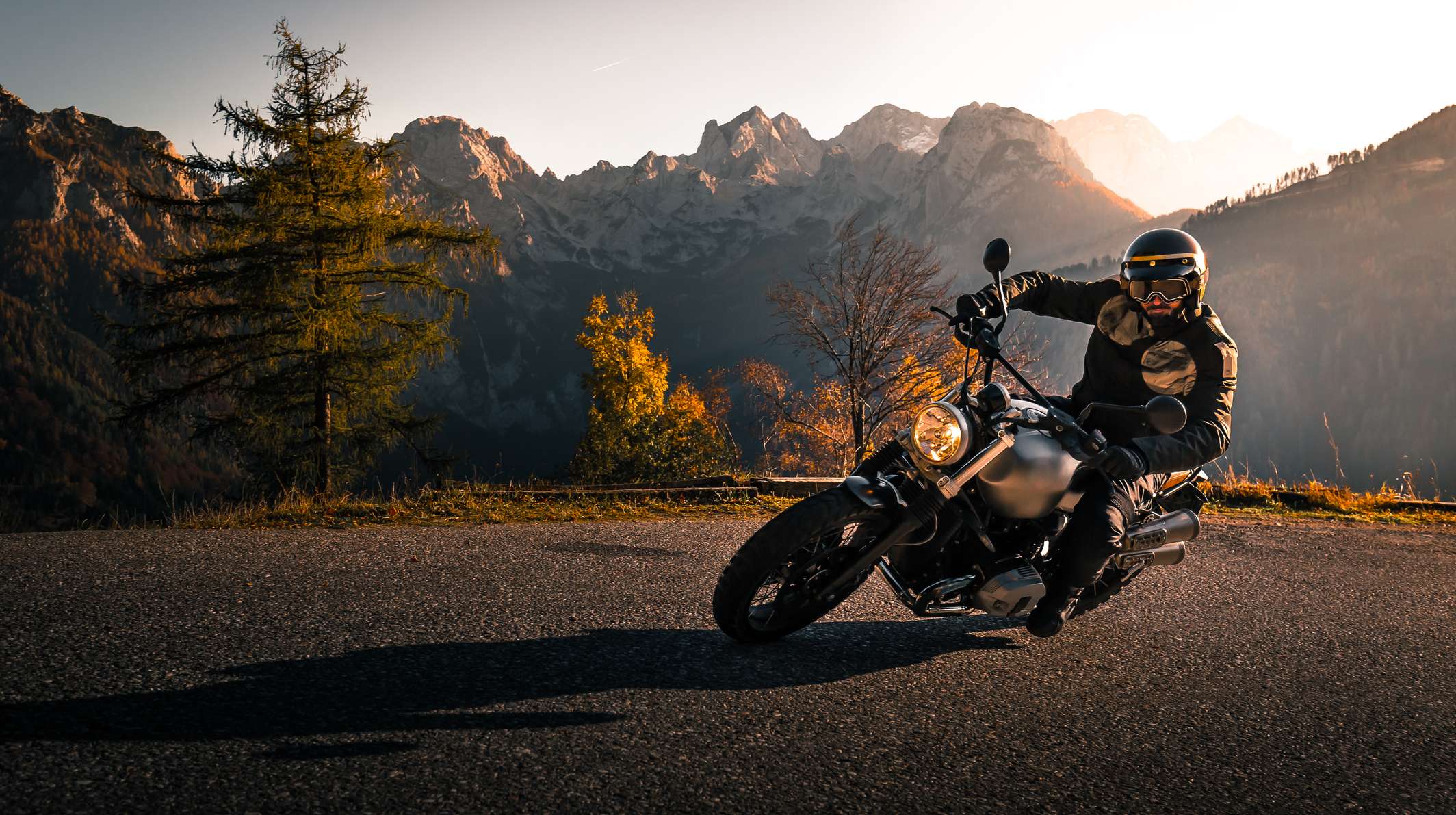 Allianz - Saisonkennzeichen Motorrad: Motorradfahrer fährt auf Passstraße durch die Berge