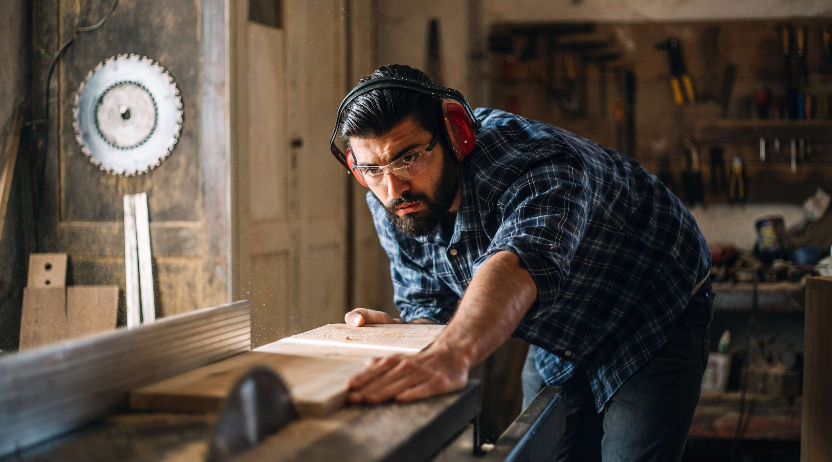 Ein Mann steht in seiner Werkstatt und sägt Holz.