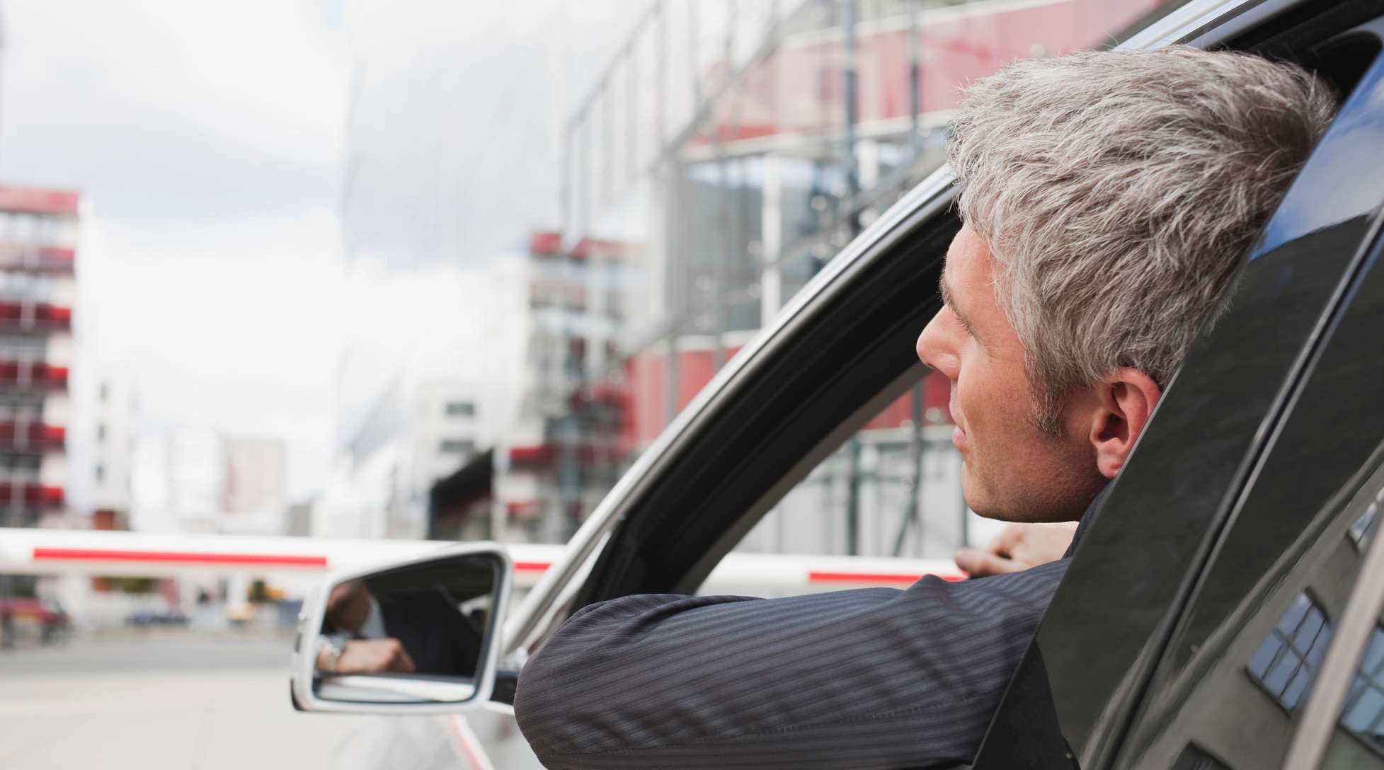 Allianz-KFZ-Haftpflichtversicherung: Mann im Auto im Anzug fahrend lehnt sich leicht aus dem Fenster