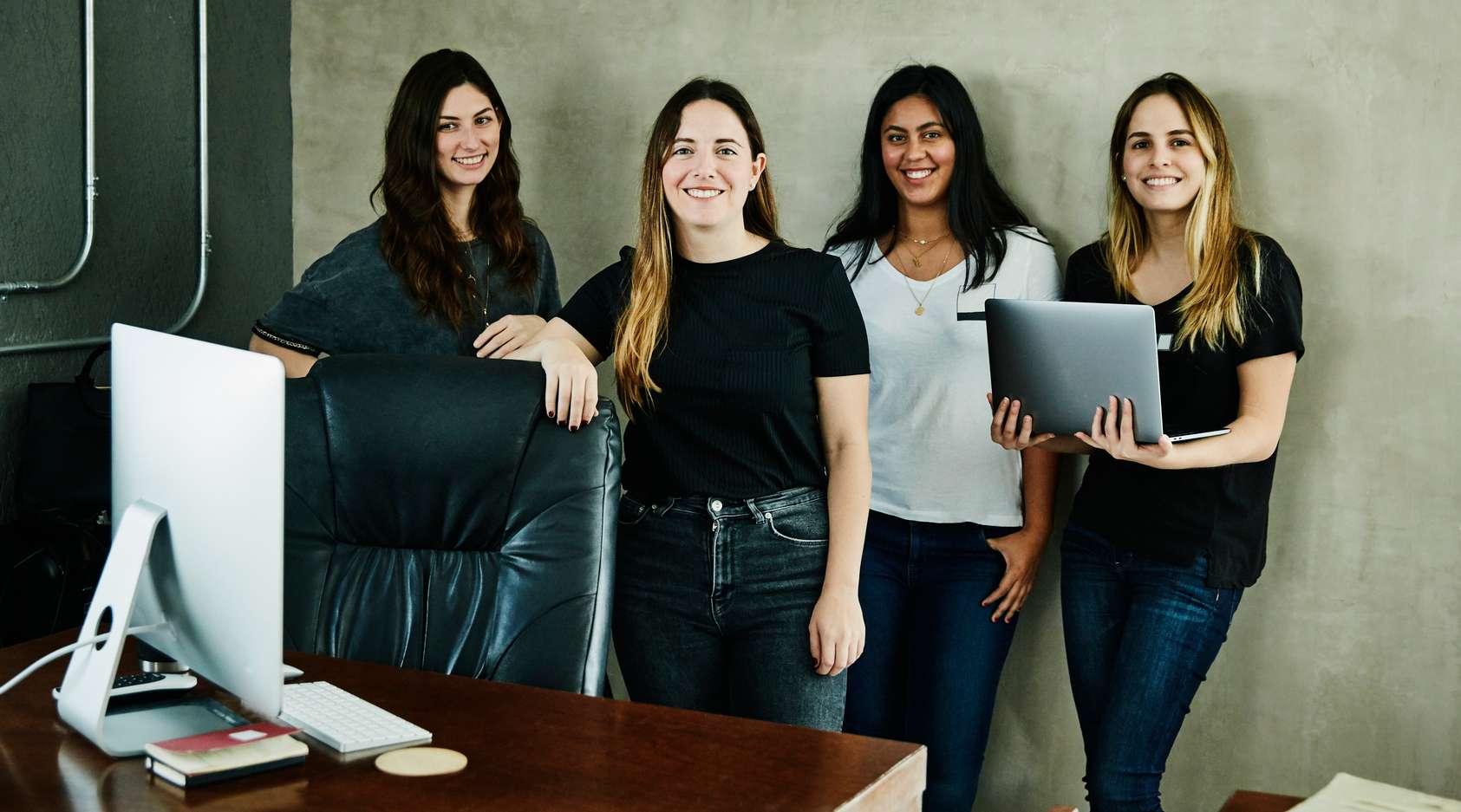 Gruppe von vier Frauen stehen zusammen in einem Büro - Versicherungen für Existenzgründer