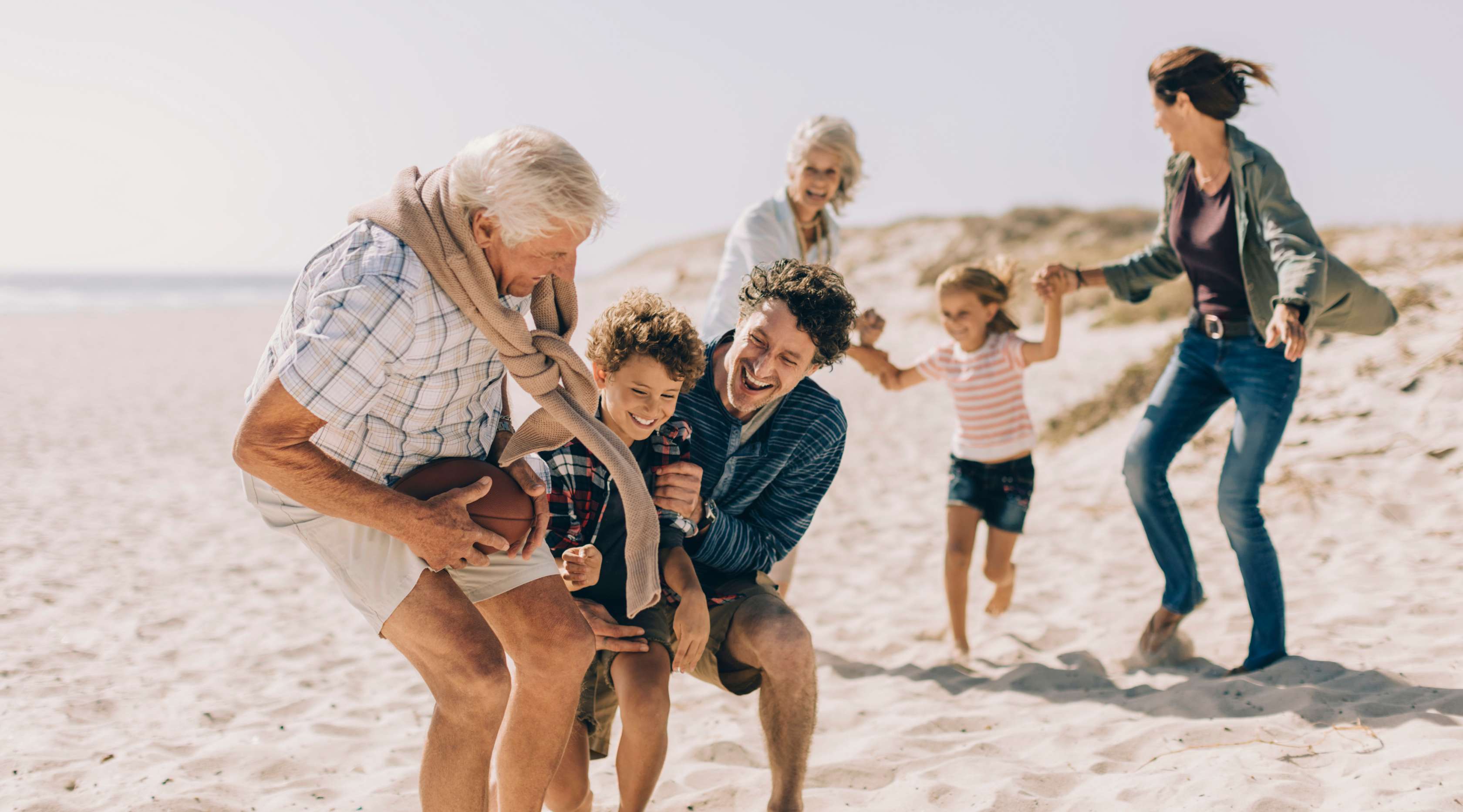 Familie mit Großeltern spielt mit den Kindern zusammen am Strand