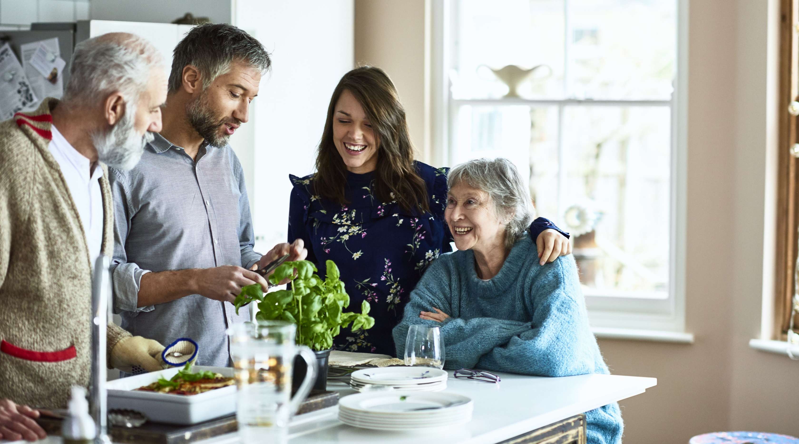 Senioren-Paar und erwachsenes Paar stehen an der Küchentheke und schauen sich etwas zusammen an