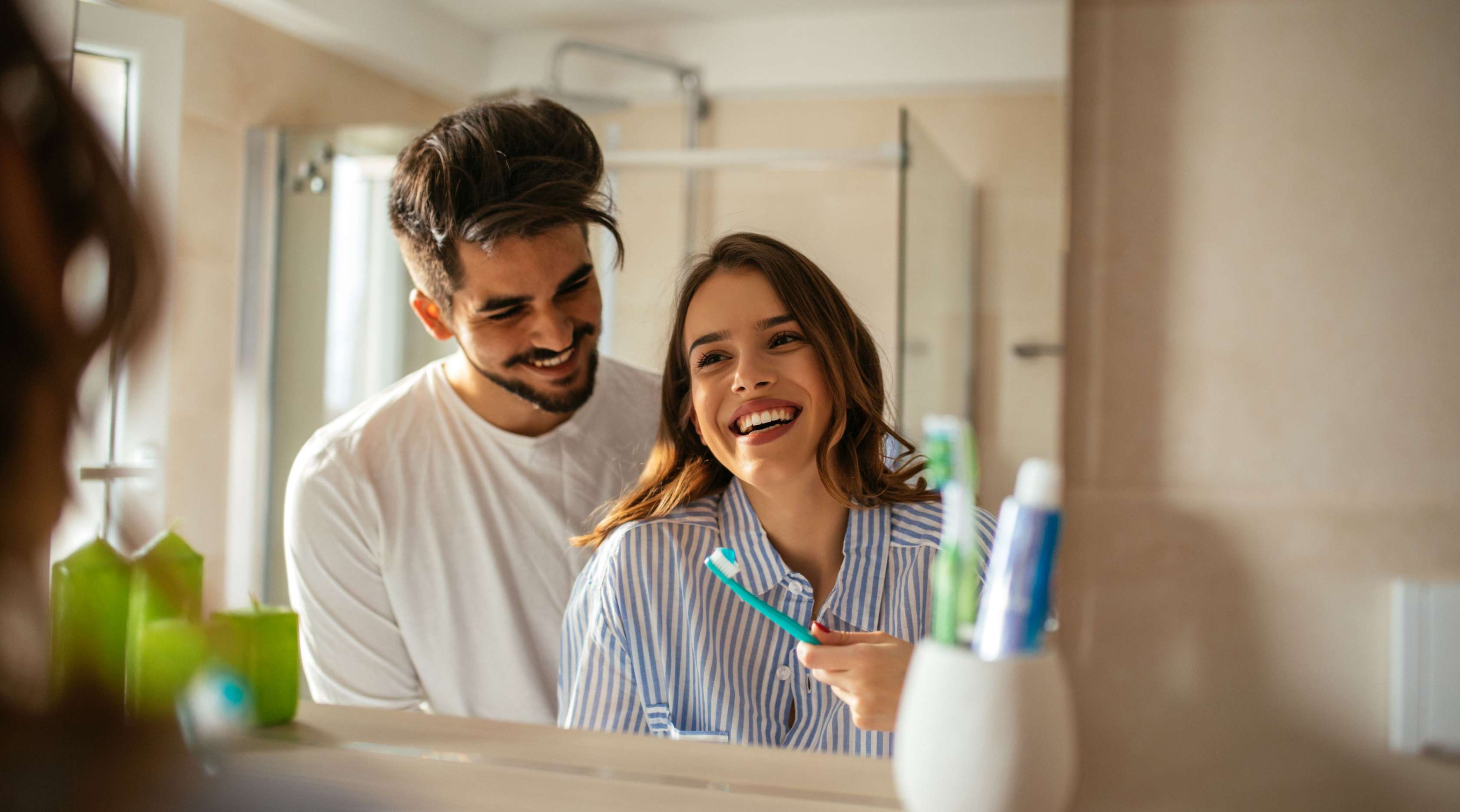 Junges Paar beim Zähneputzen im Badezimmer vor dem Spiegel 