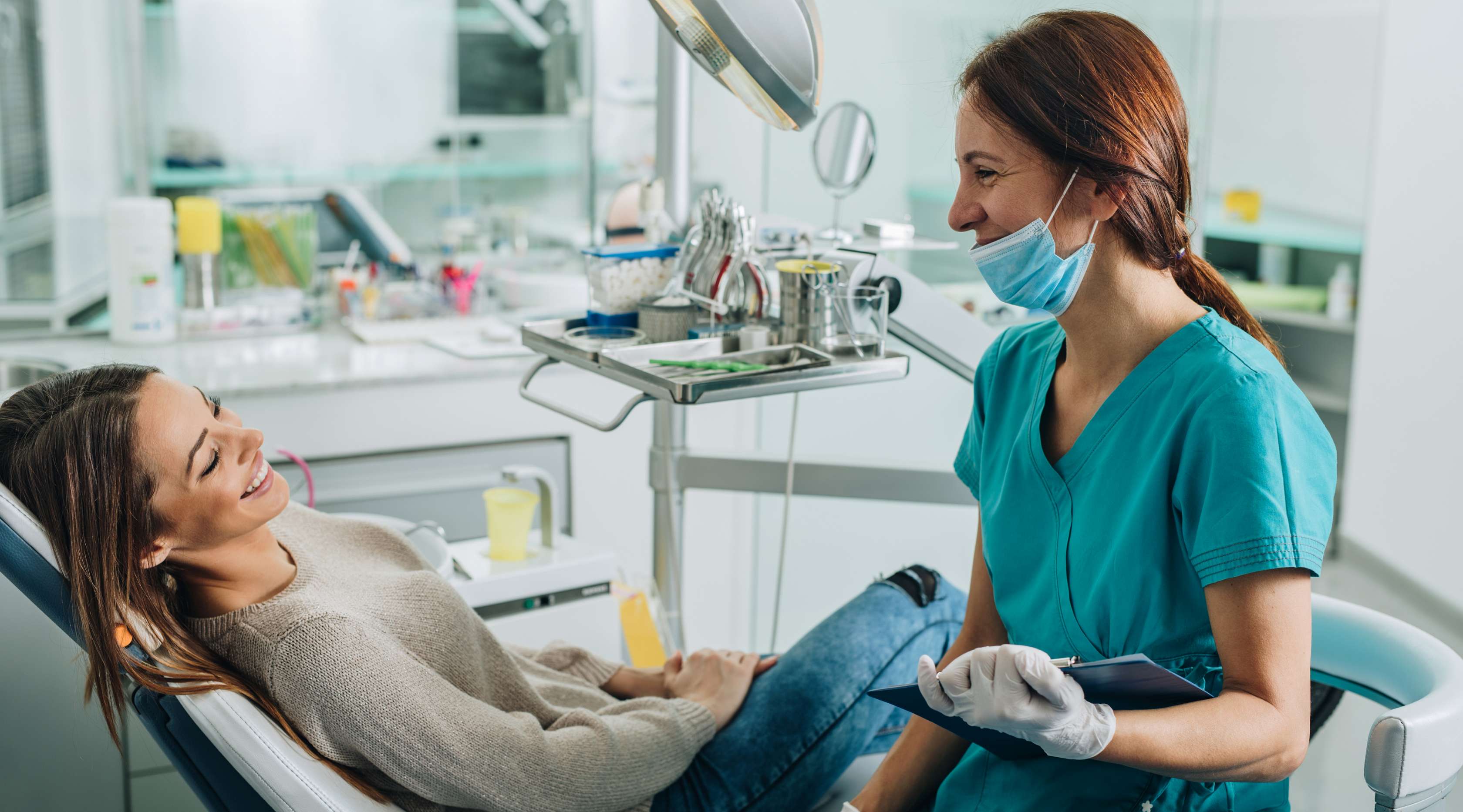 Zahnärztin spricht mit Patient auf Zahnarztstuhl