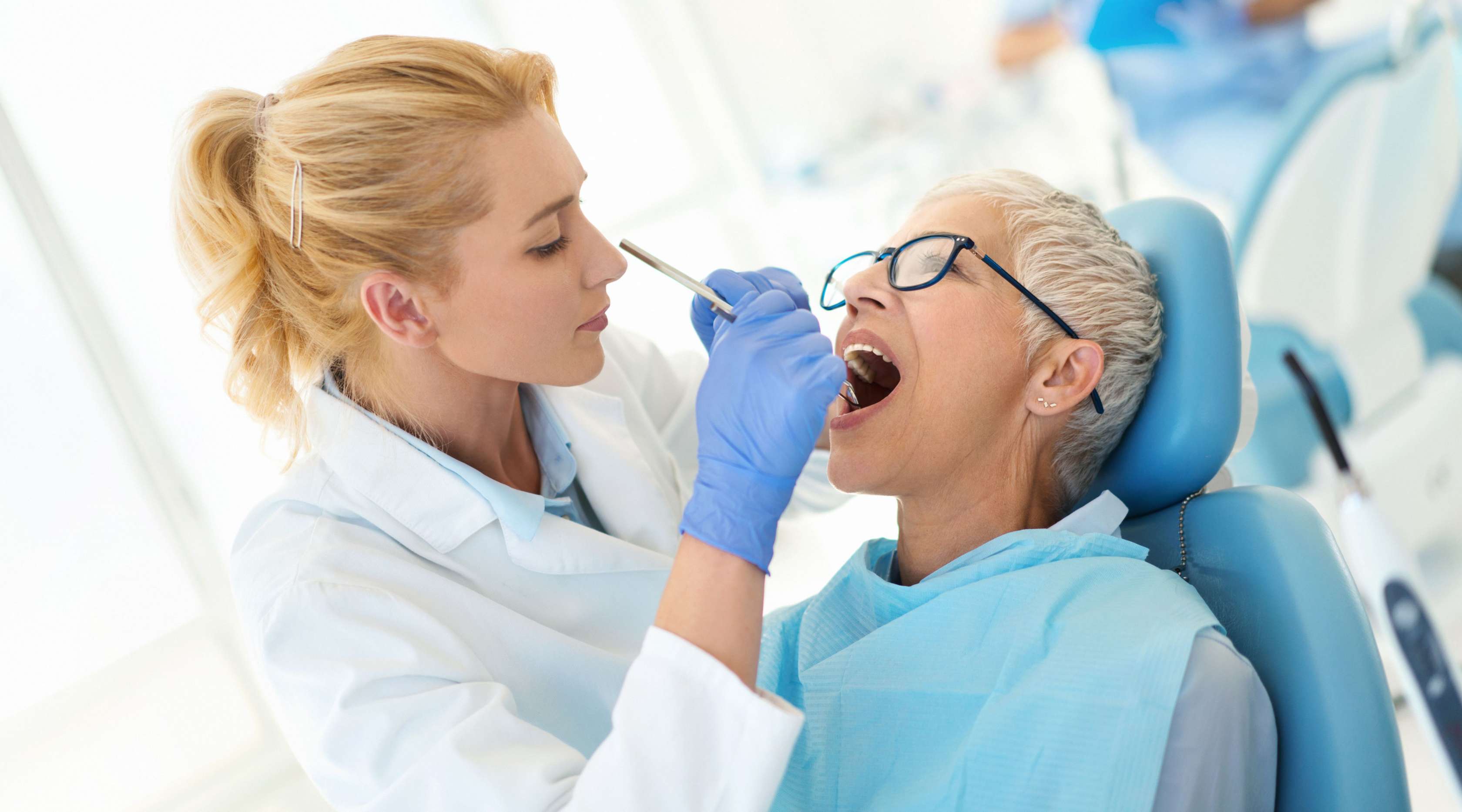 Zahnarzt schaut sich die Zähne einer Patientin an
