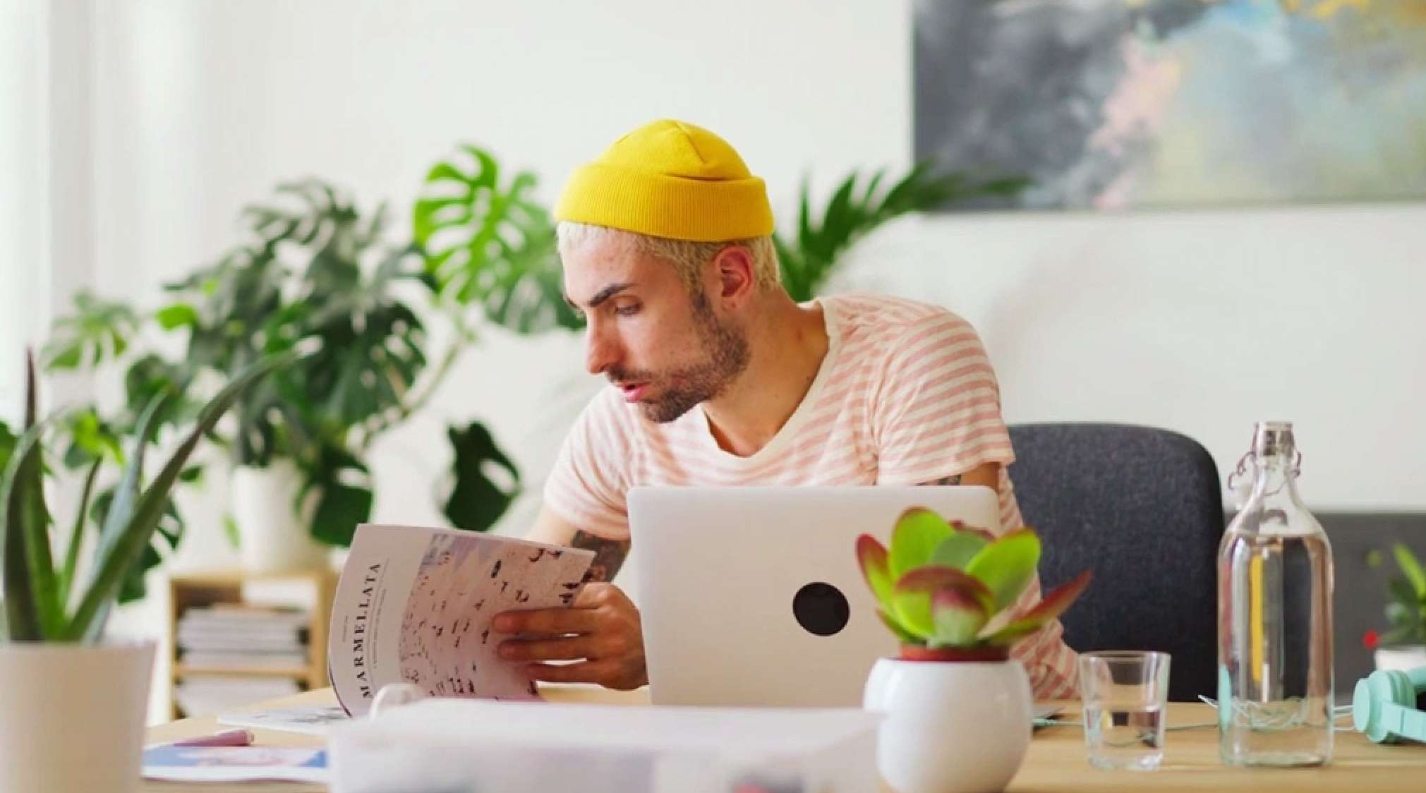 Junger Mann mit gelber Mütze liest eine Zeitschrift