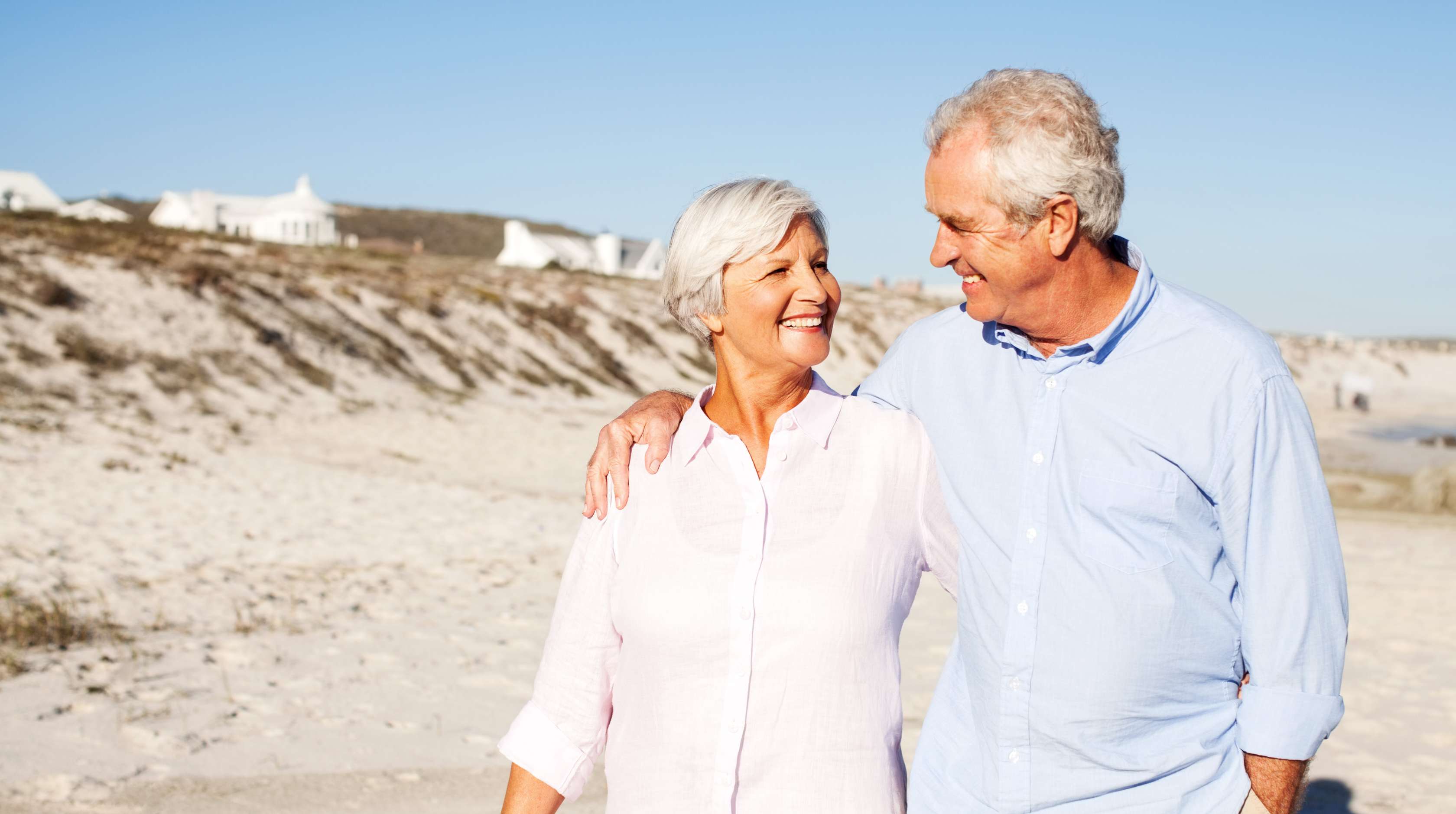Allianz - Riester Rente: Älteres Paar spaziert glücklich am Strand