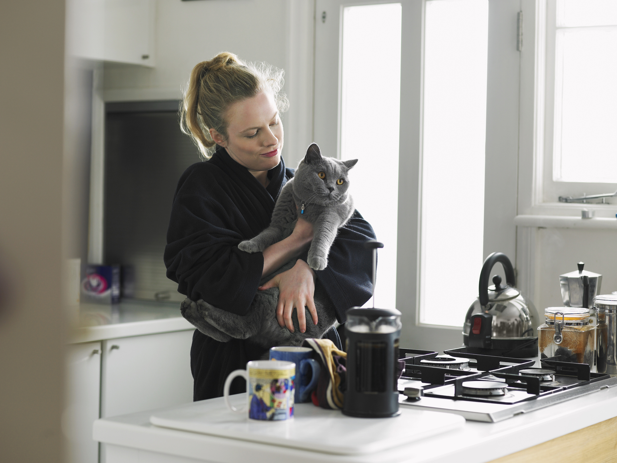 Allianz - Katze Barfen: Frauchen steht in der Küche und hält ihre Katze im Arm