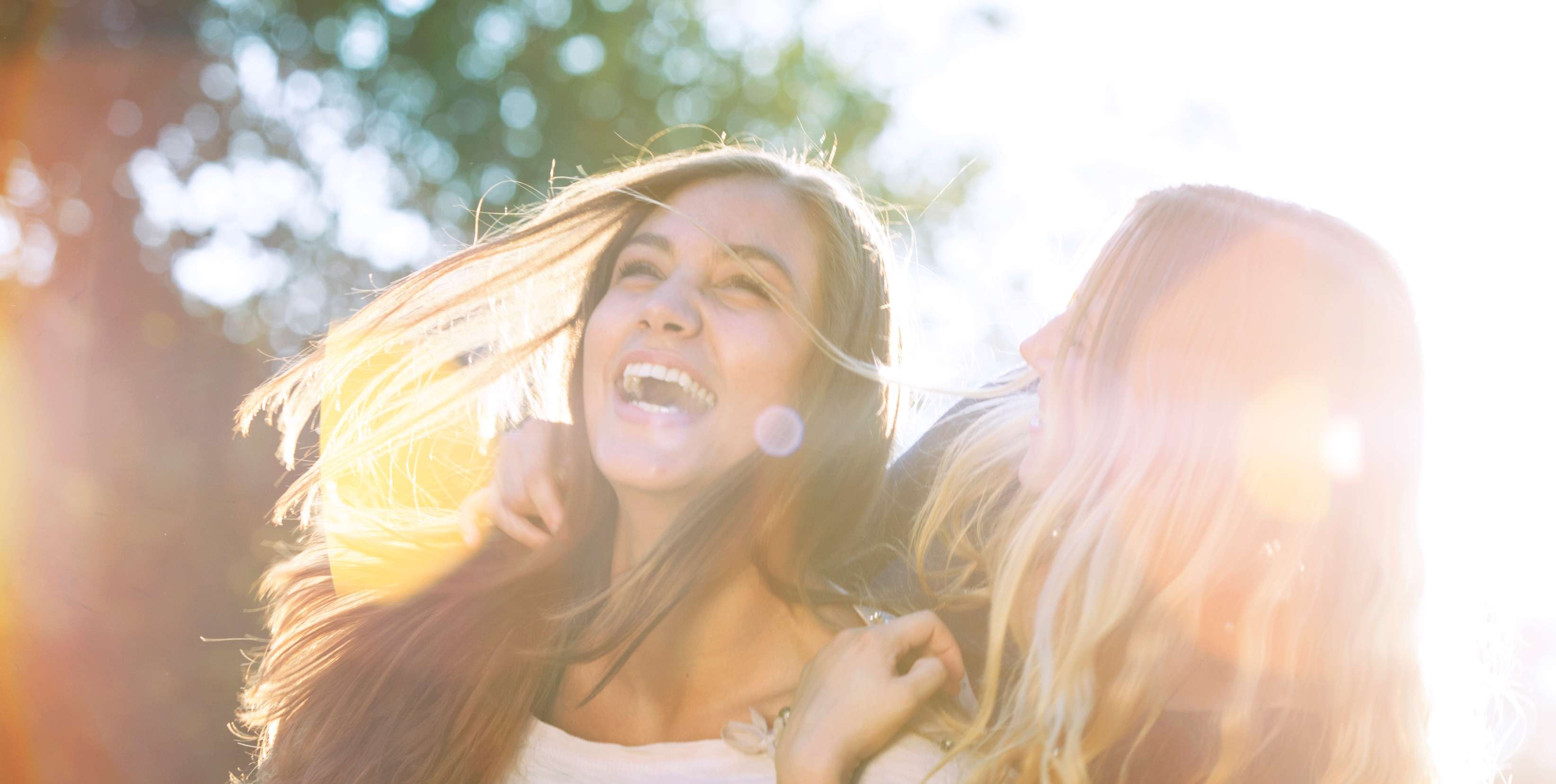 Allianz private Krankenzusatzversicherung: Zwei Frauen sind draußen in der Natur, umarmen sich und sind glücklich.