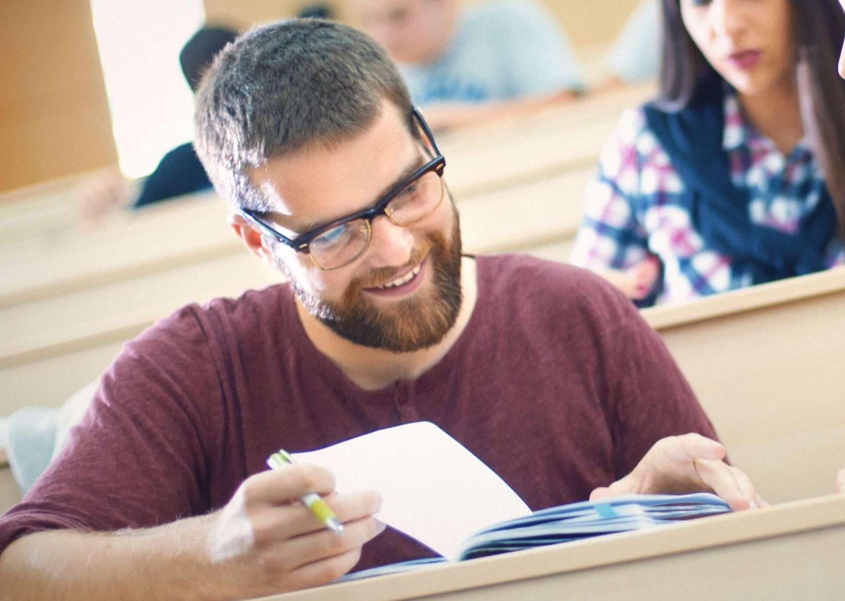 Student und Studentin schauen im Hörsaal gemeinsam Notizen in einem Ordner an.