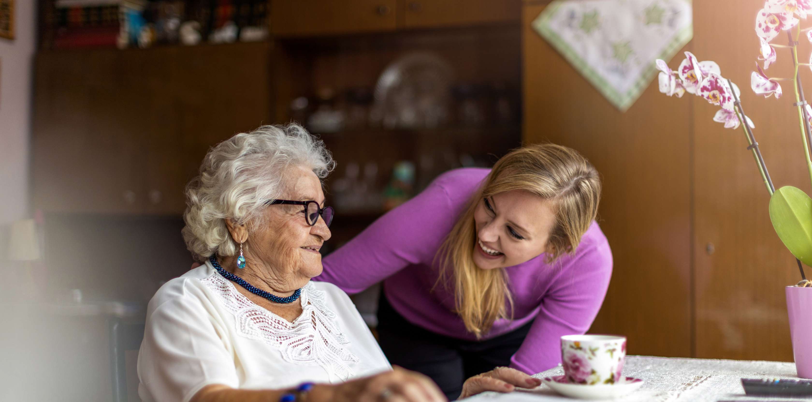 Ältere Frau mit Pflegerin zuhause am Esstisch