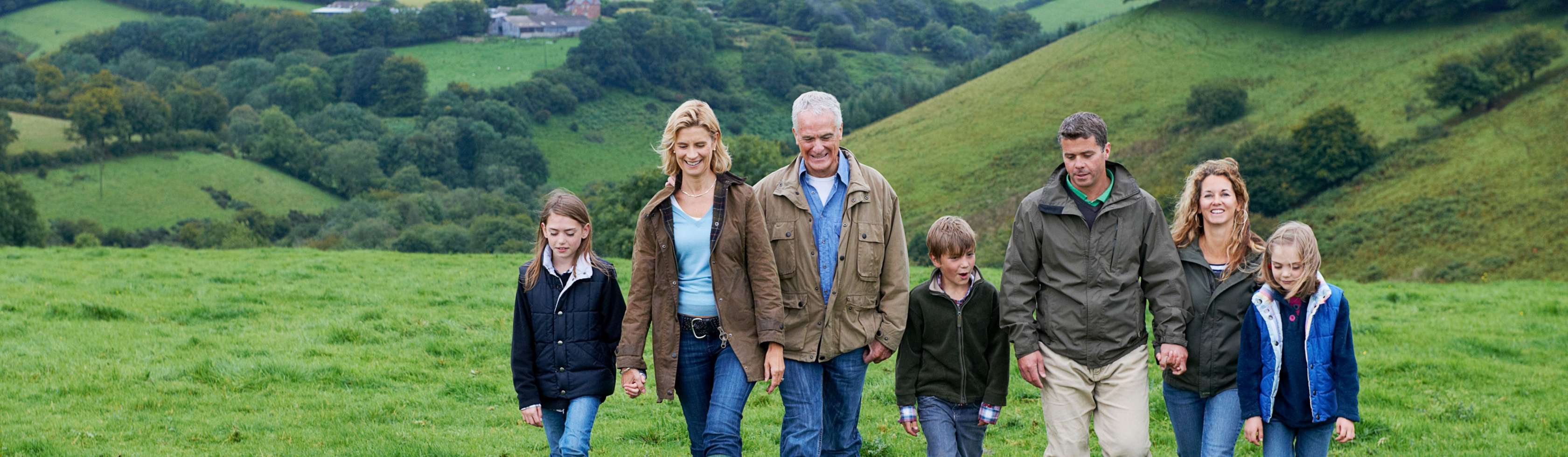 Eine drei Generationen Familie spaziert in einer Hügellandschaft