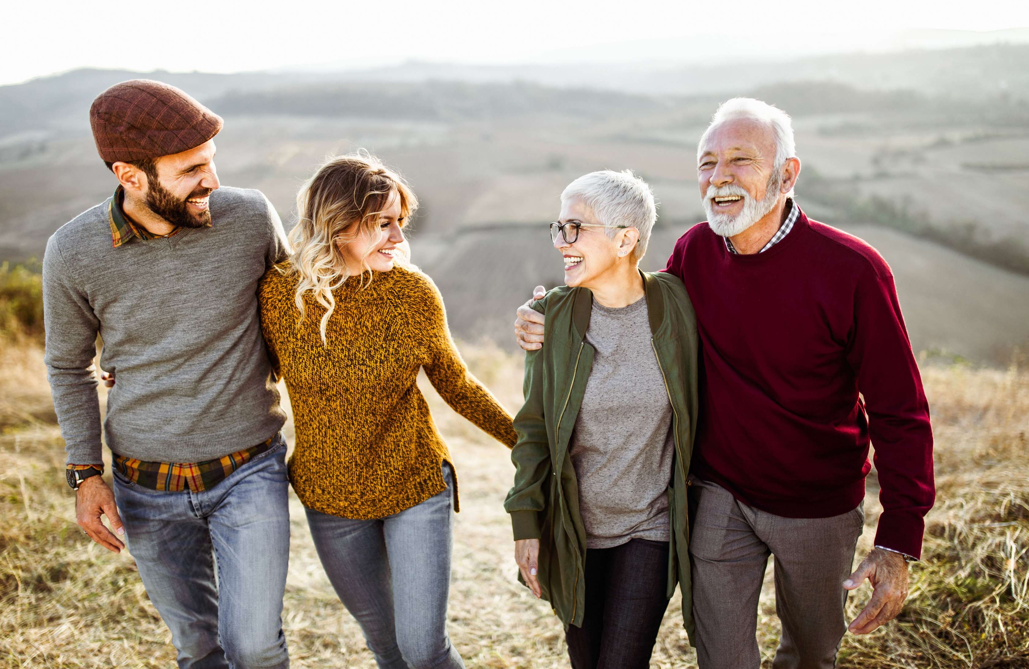 Warum ist eine private Pflegezusatz­versicherung der Allianz sinnvoll? Eine Familie geht nebeneinander spazieren, dabei halten sich die Partner:innen im Arm. 