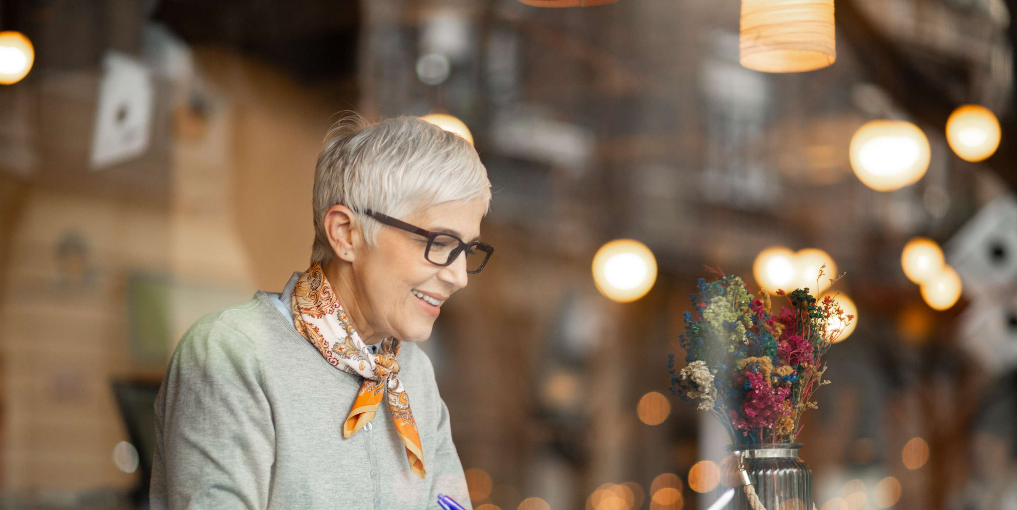 Allianz Alterungs­rückstellungen in der privaten Kranken­versicherung. Eine Ältere Frau in einem Cafe macht Notizen.