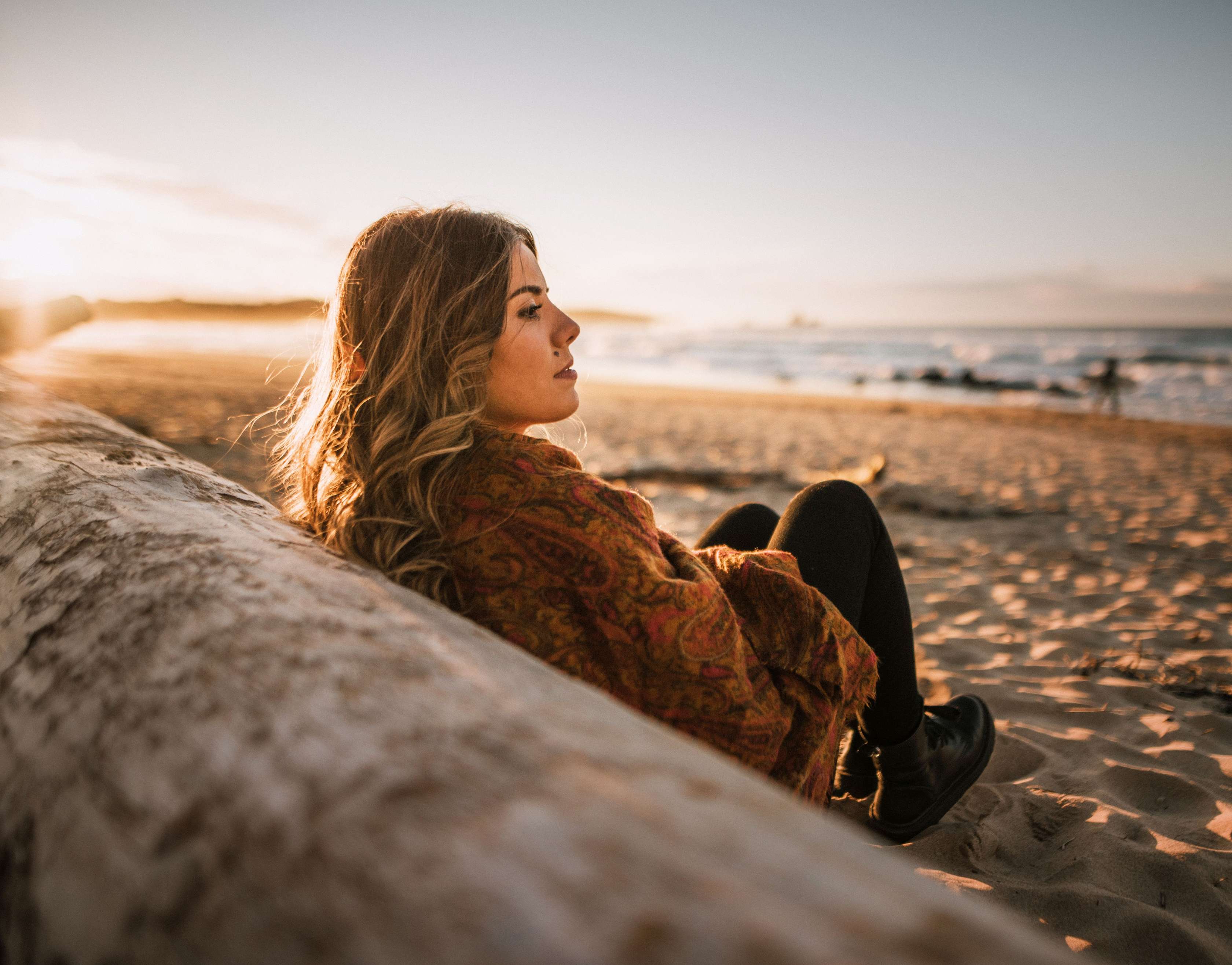 Allianz Private Kranken­versicherung Anwart­schafts­versicherung: Junge Frau sitzt am Strand und schaut zum Meer