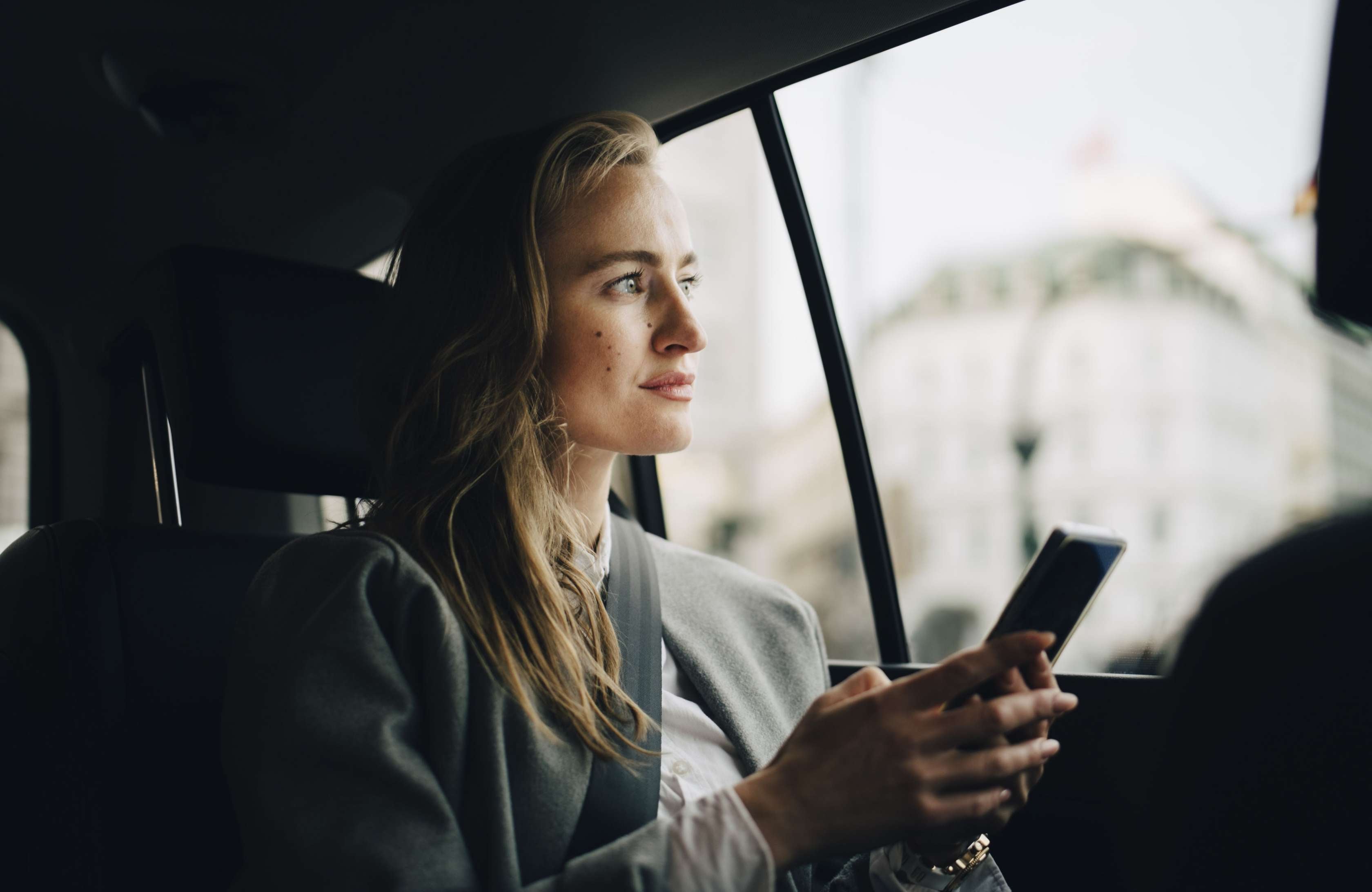 Allianz - Private Krankenversicherung bei Arbeitslosigkeit. Eine Frau sitzt im Auto und schaut in die Ferne.