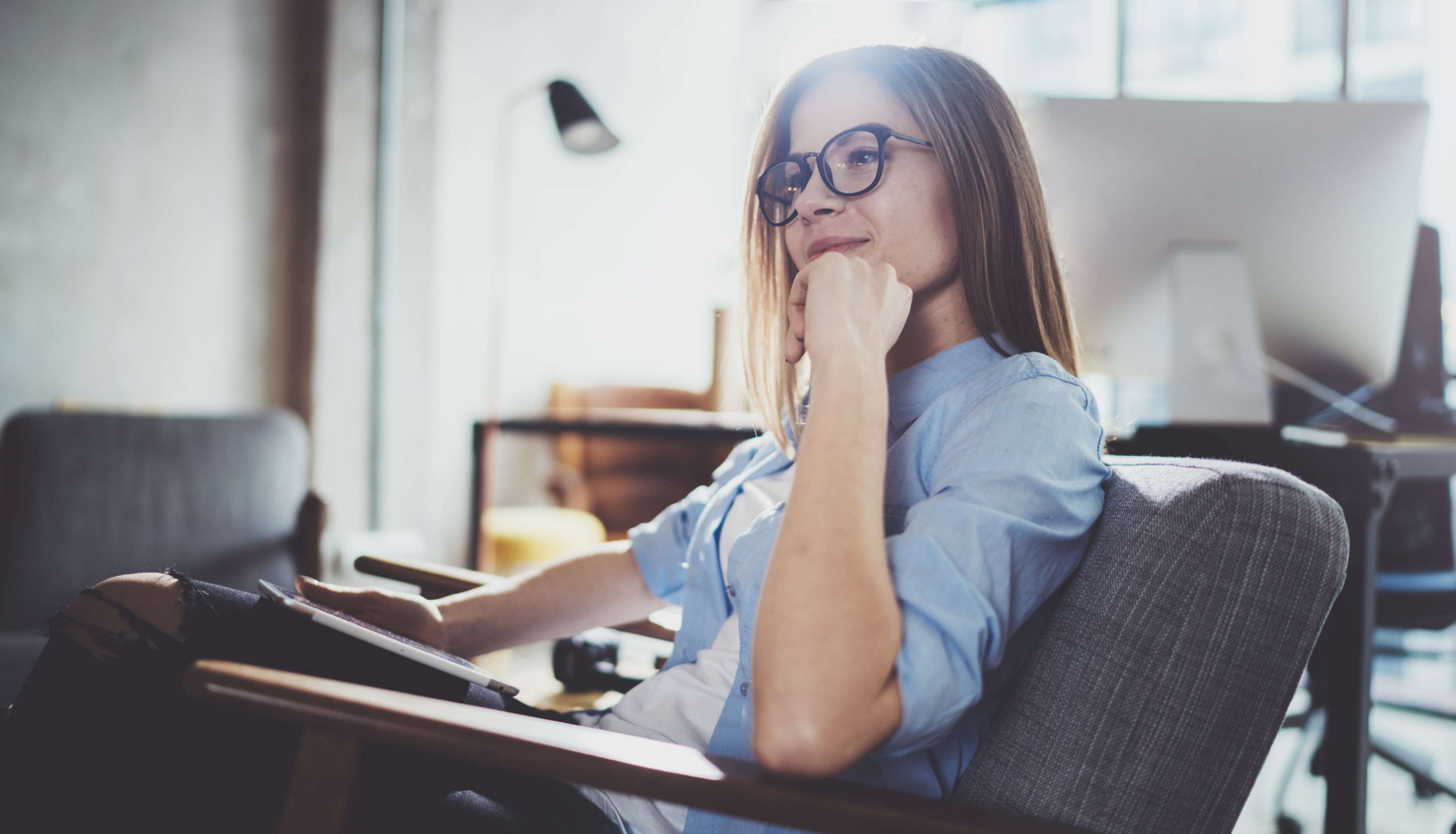 Allianz Private Krankenversicherung: Krankengeld und Krankentagegeld im Vergleich. Eine Frau sitzt nachdenklich auf einem Sessel.