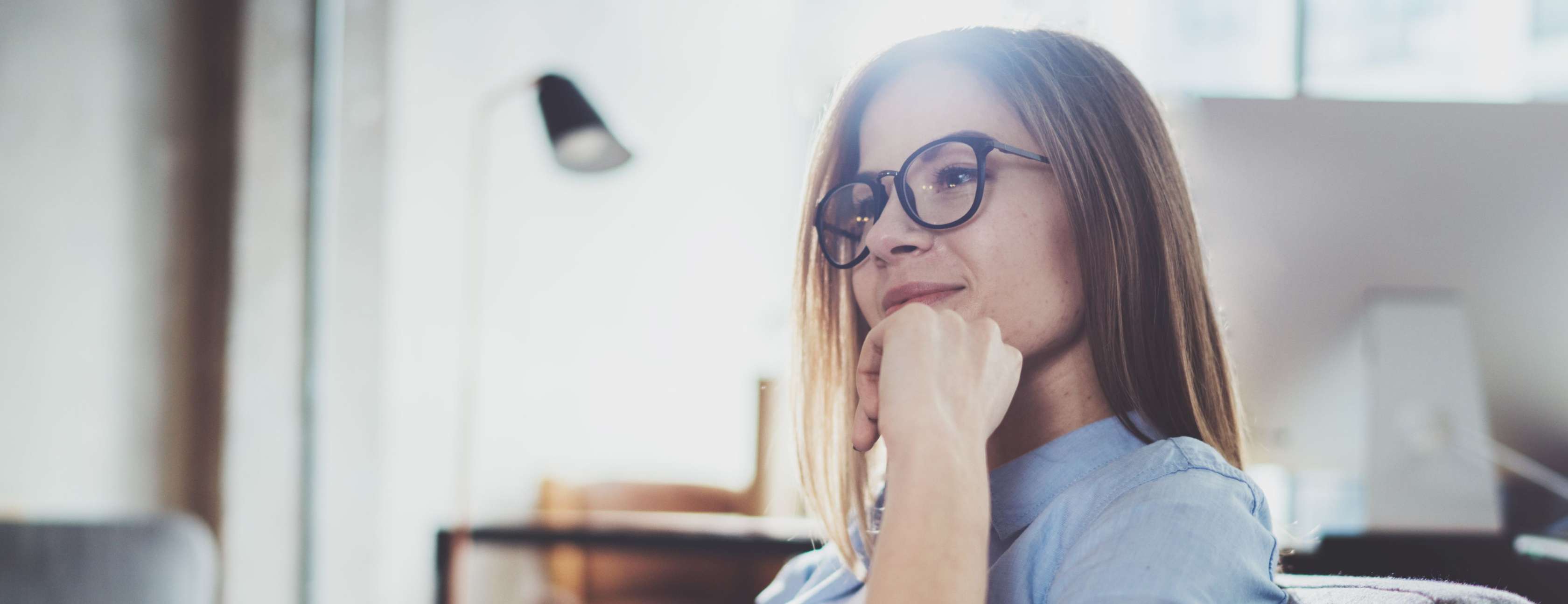 Allianz Private Krankenversicherung: Krankengeld und Krankentagegeld im Vergleich. Eine Frau sitzt nachdenklich auf einem Sessel.