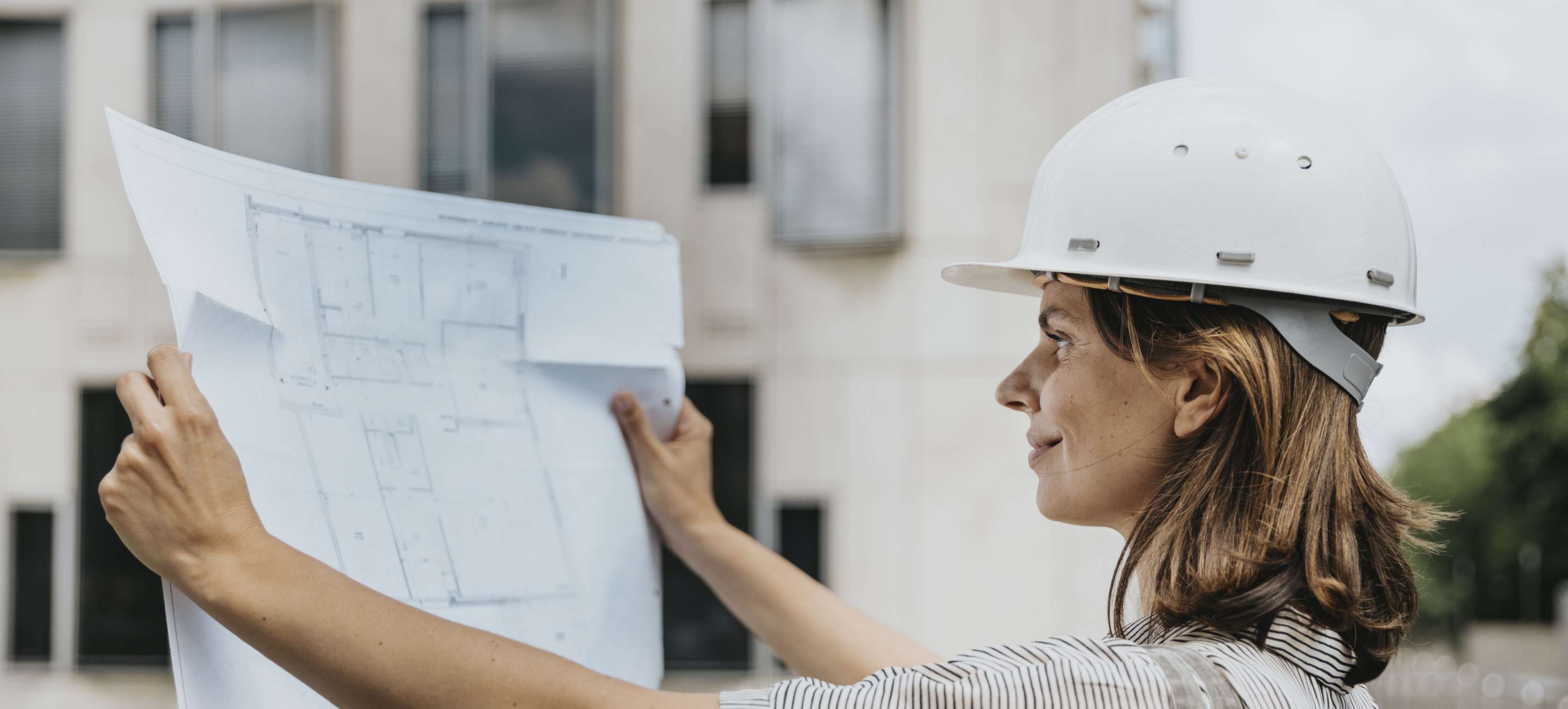 Allianz Private Krankenversicherung: Leistungen. Eine Bauleiterin schaut sich vor der Baustelle einen Plan an.