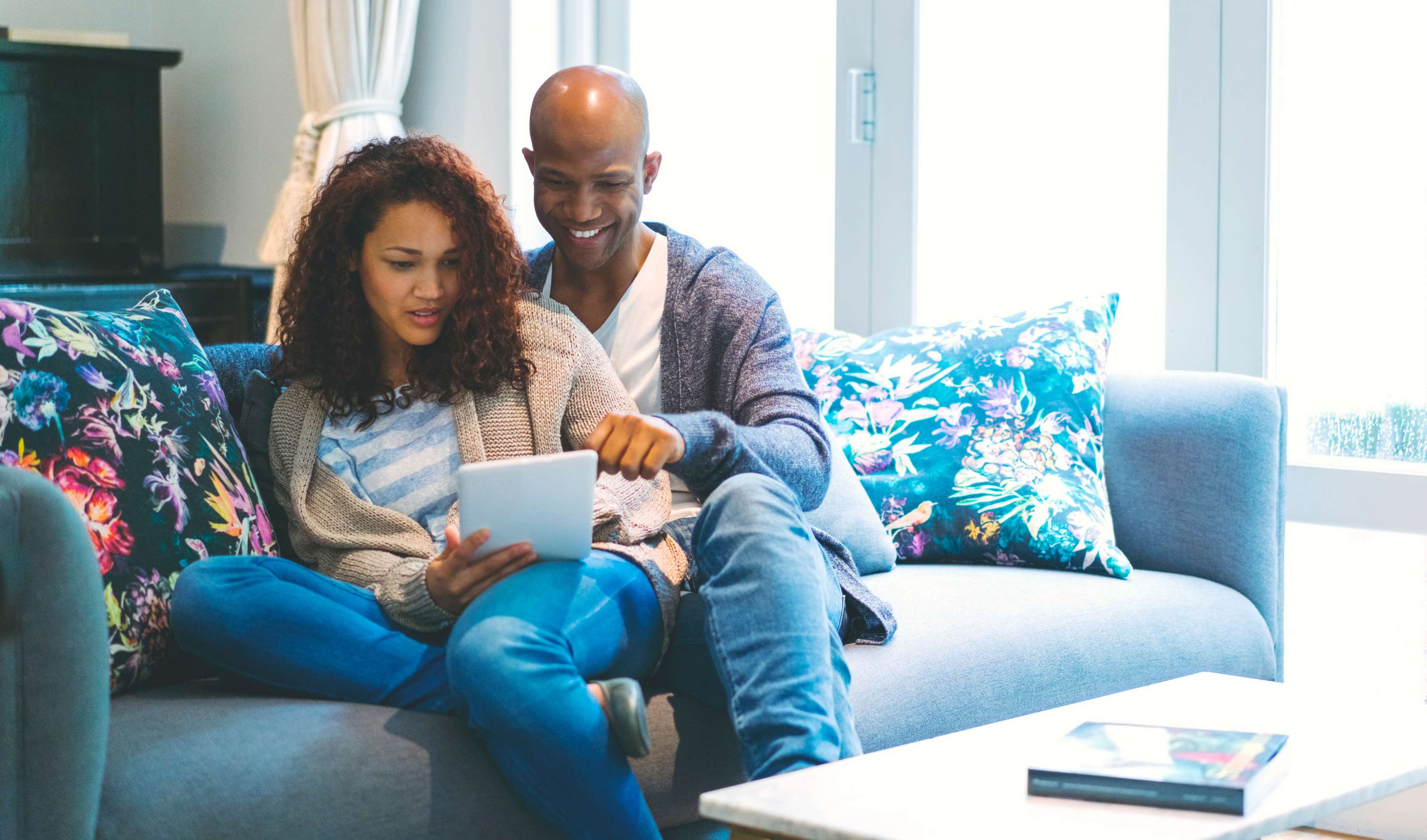 Allianz Private Krankenversicherung online abschließen. So funktioniert der digitale Abschluss einer privaten Krankenversicherung. Ein Paar sitzt auf dem Sofa und schauen sich ein Dokument an.