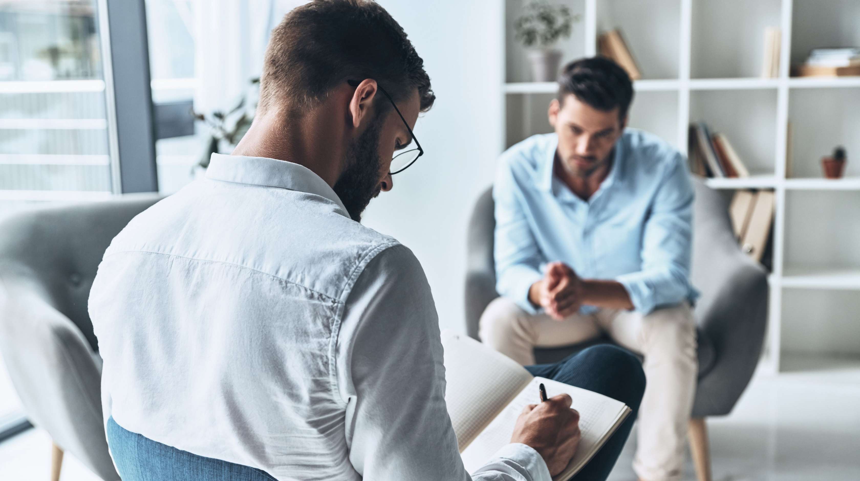 Allianz Psychotherapie in der privaten Krankenversicherung: Behandlung und Abrechnung einfach erklärt. Zwei Männer sitzen sich gegenüber und unterhalten sich.