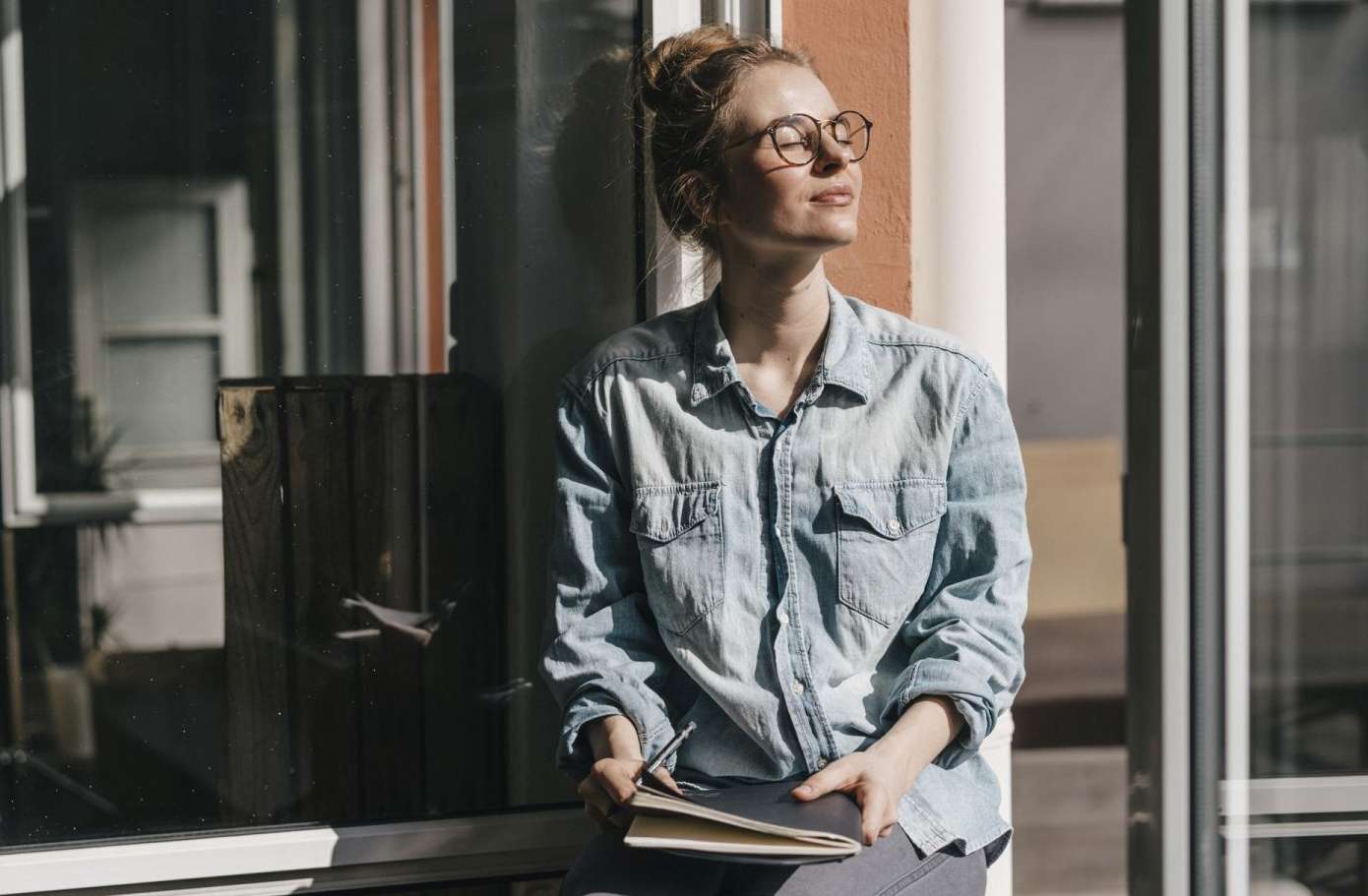 Allianz Private Krankenversicherung trotz Vorerkrankung: Frau lehnt an der Wand und genießt die Sonne