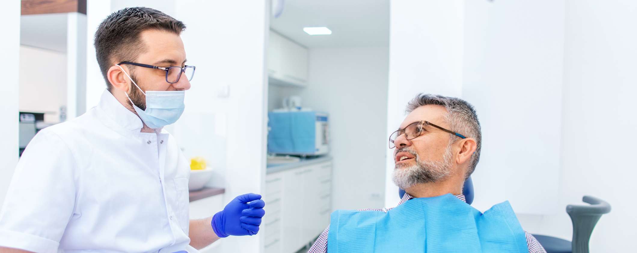 Arzt erläutert dem Patienten Kosten für einen Zahnersatz Festzuschuss