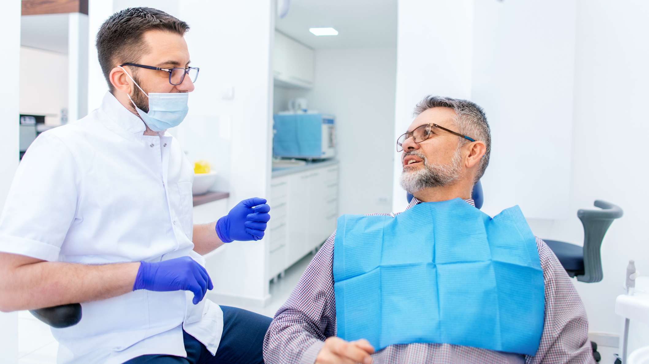 Arzt erläutert dem Patienten Kosten für einen Zahnersatz Festzuschuss