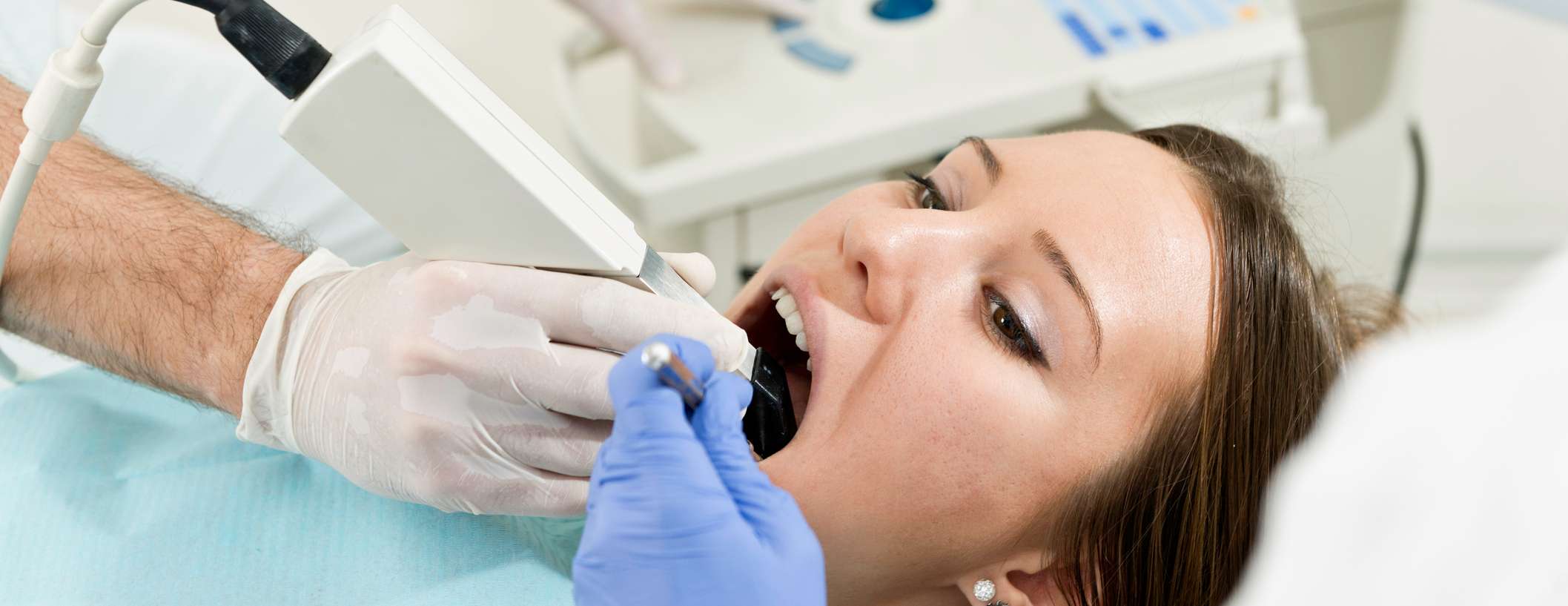 Eine Frau befindet sich bei einer Untersuchung beim Zahnarzt und öffnet den Mund