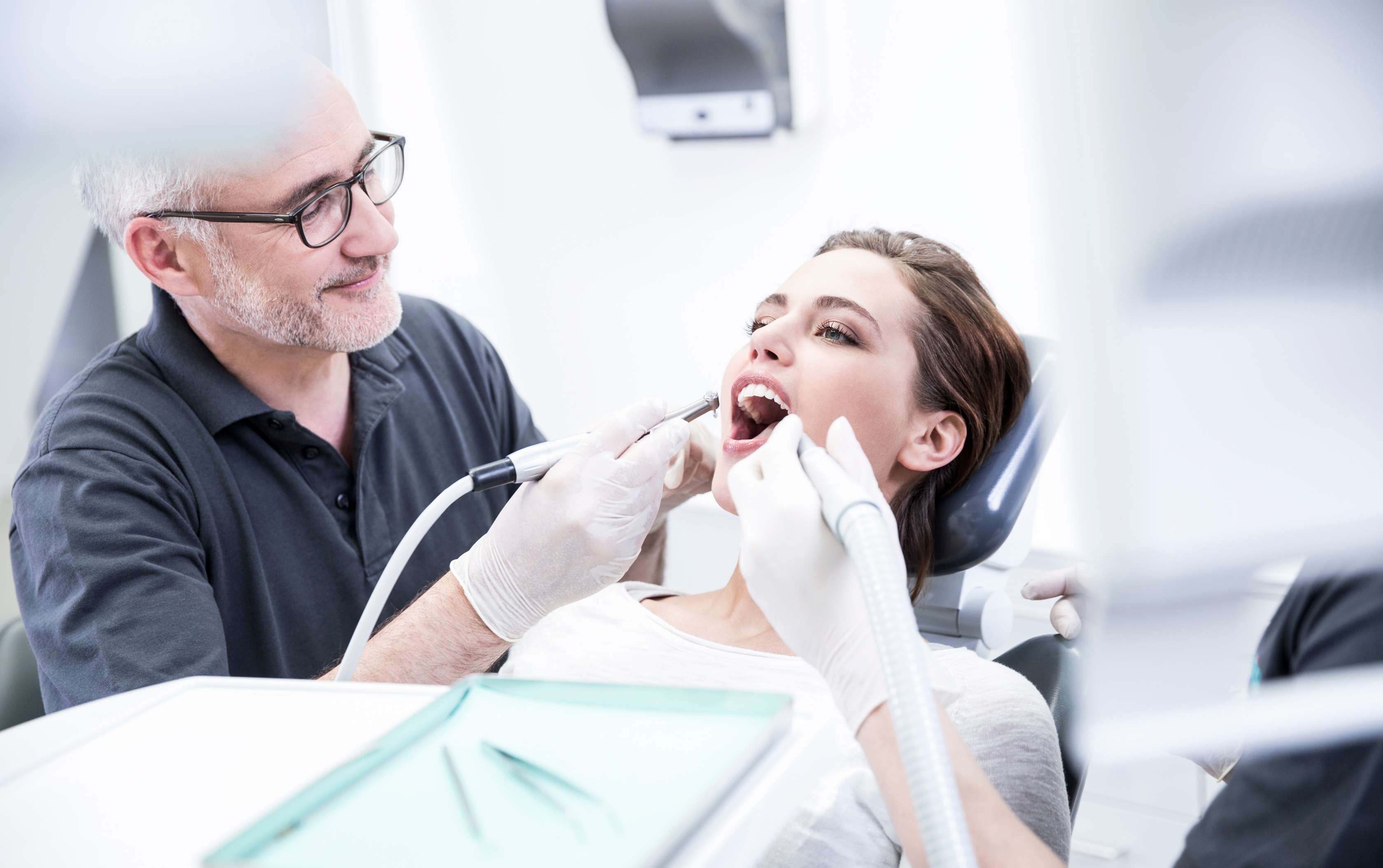 Zahnzusatzversicherung ohne Wartezeit: Ein Zahnarzt untersucht das Gebiss einer Patientin