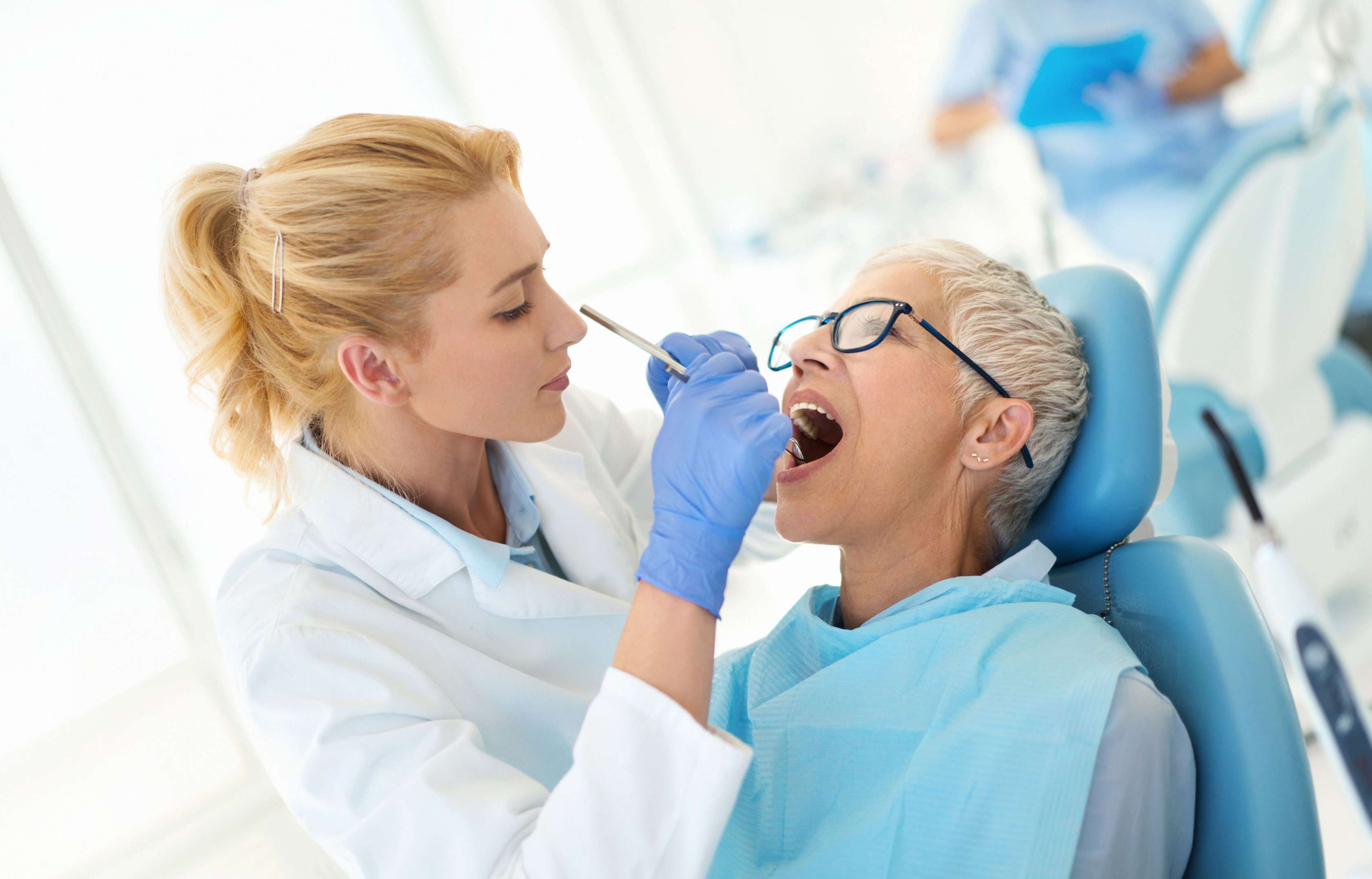 Zahnarzt schaut sich die Zähne einer Patientin an