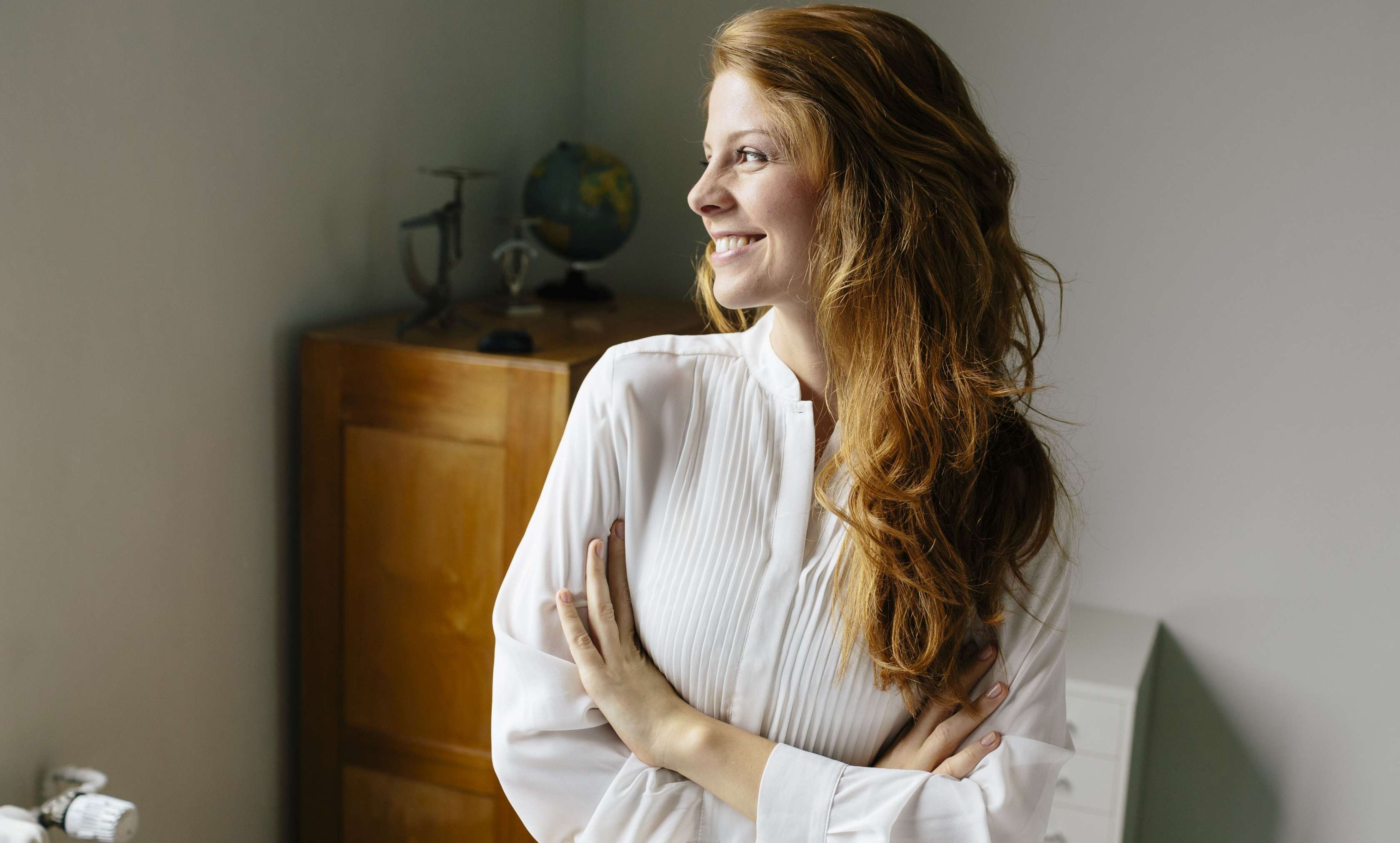 Allianz Zahnkorrektur: Eine Frau schaut lachend aus dem Fenster