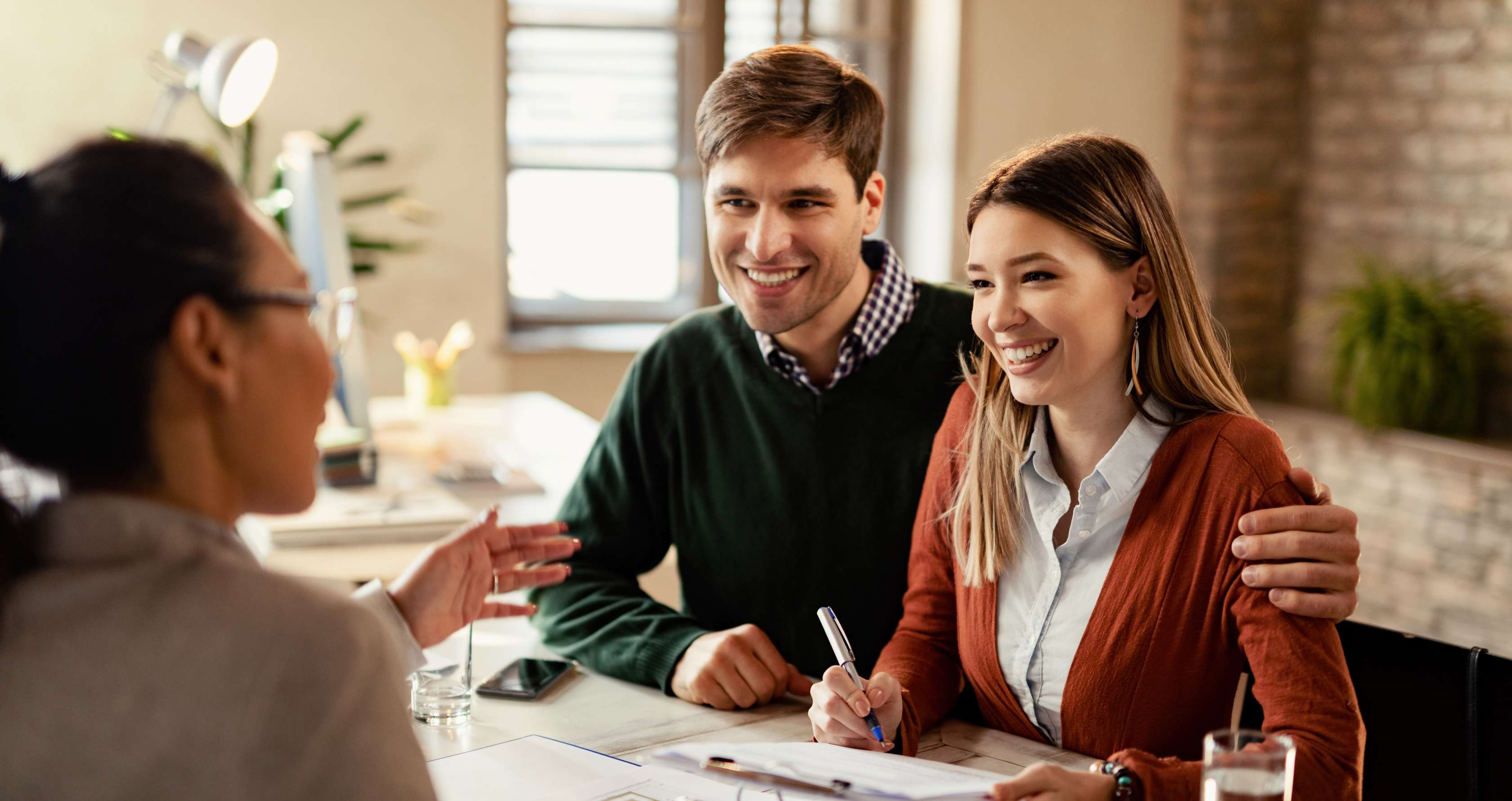 Allianz Annuitätendarlehen: Junges Paar unterschreibt Kreditvertrag für Hausbau