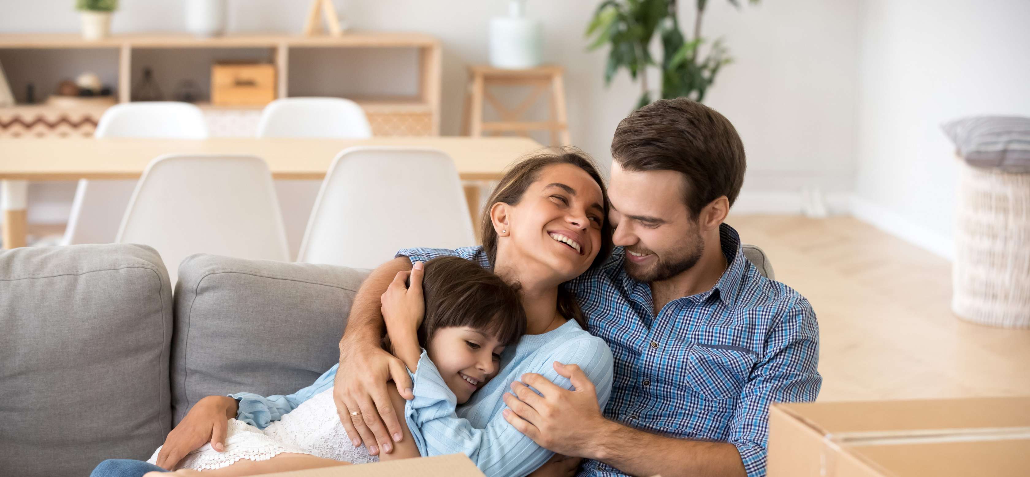 Allianz Volltilgerdarlehen - Junge Familie glücklich im Wohnzimmer mit Umzugskartons.