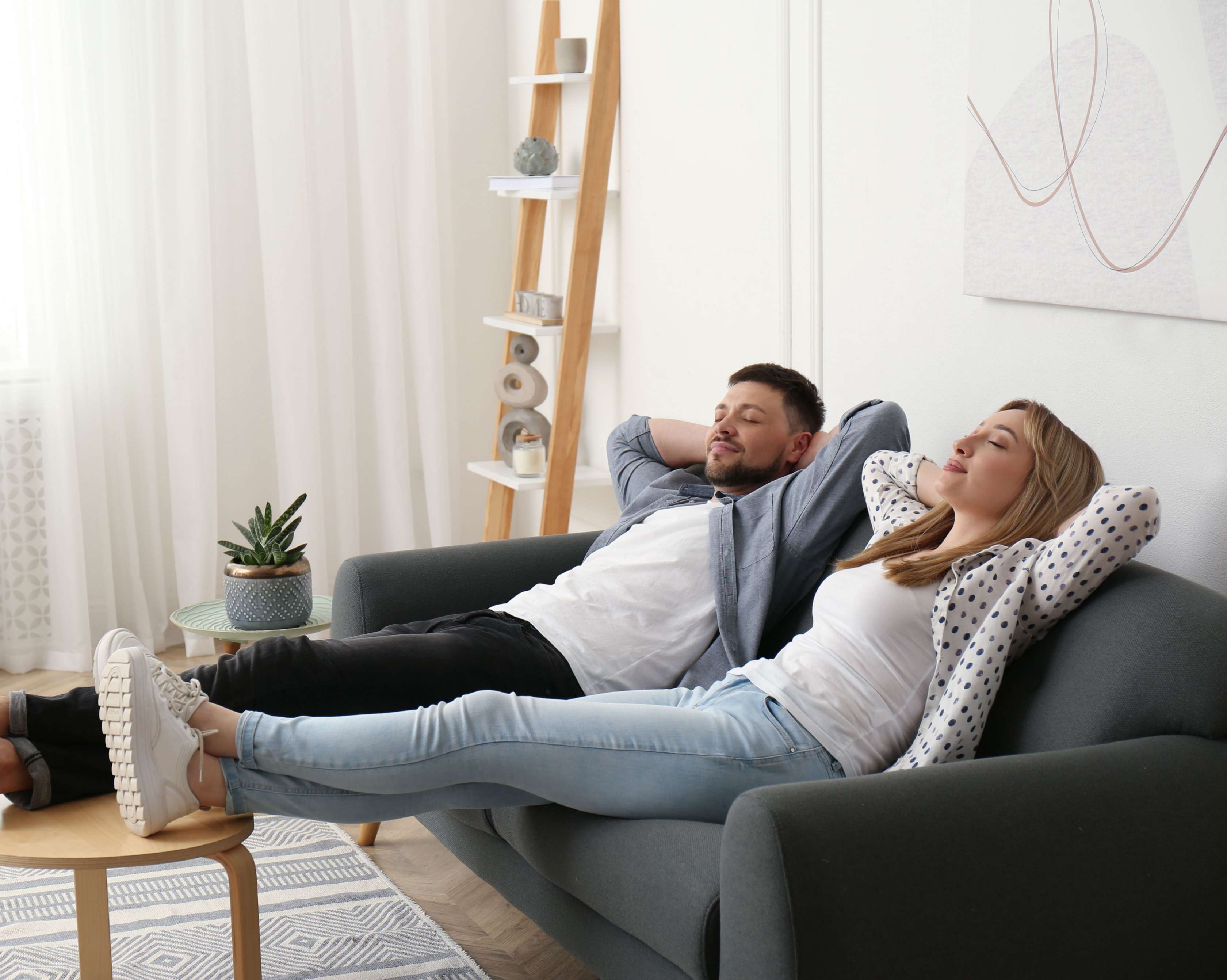 Allianz Volltilgerdarlehen - Junges Paar entspannt auf Sofa im Wohnzimmer.