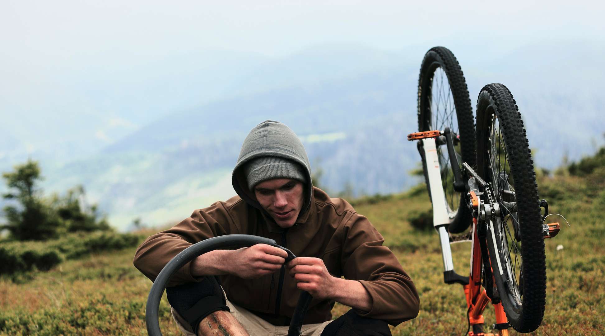  Mann flickt auf Berghügel Mountainbike-Schlauch