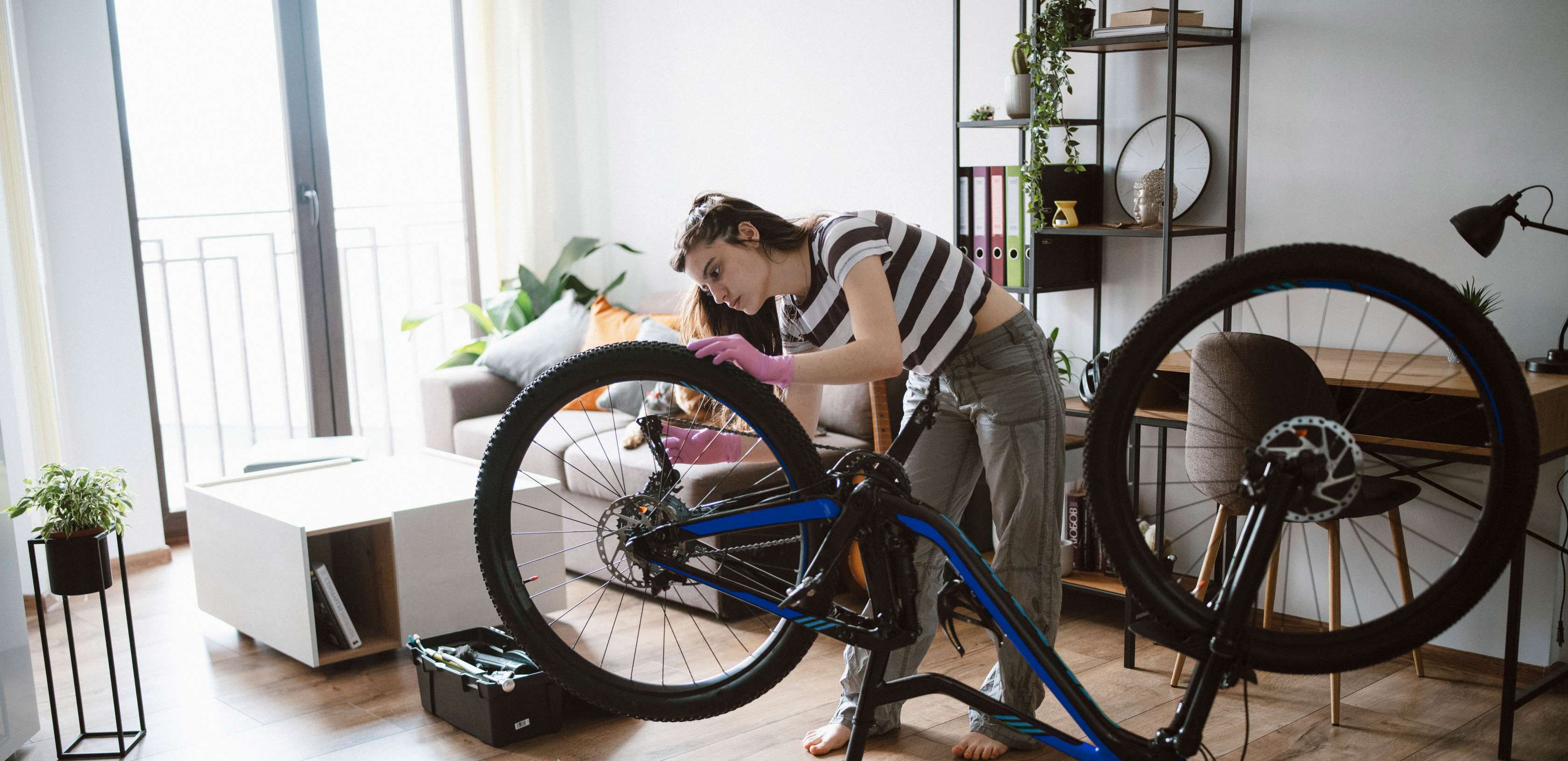 Gegenstandsschutz: Junge Frau repariert ein Fahrrad in ihrer Wohnung