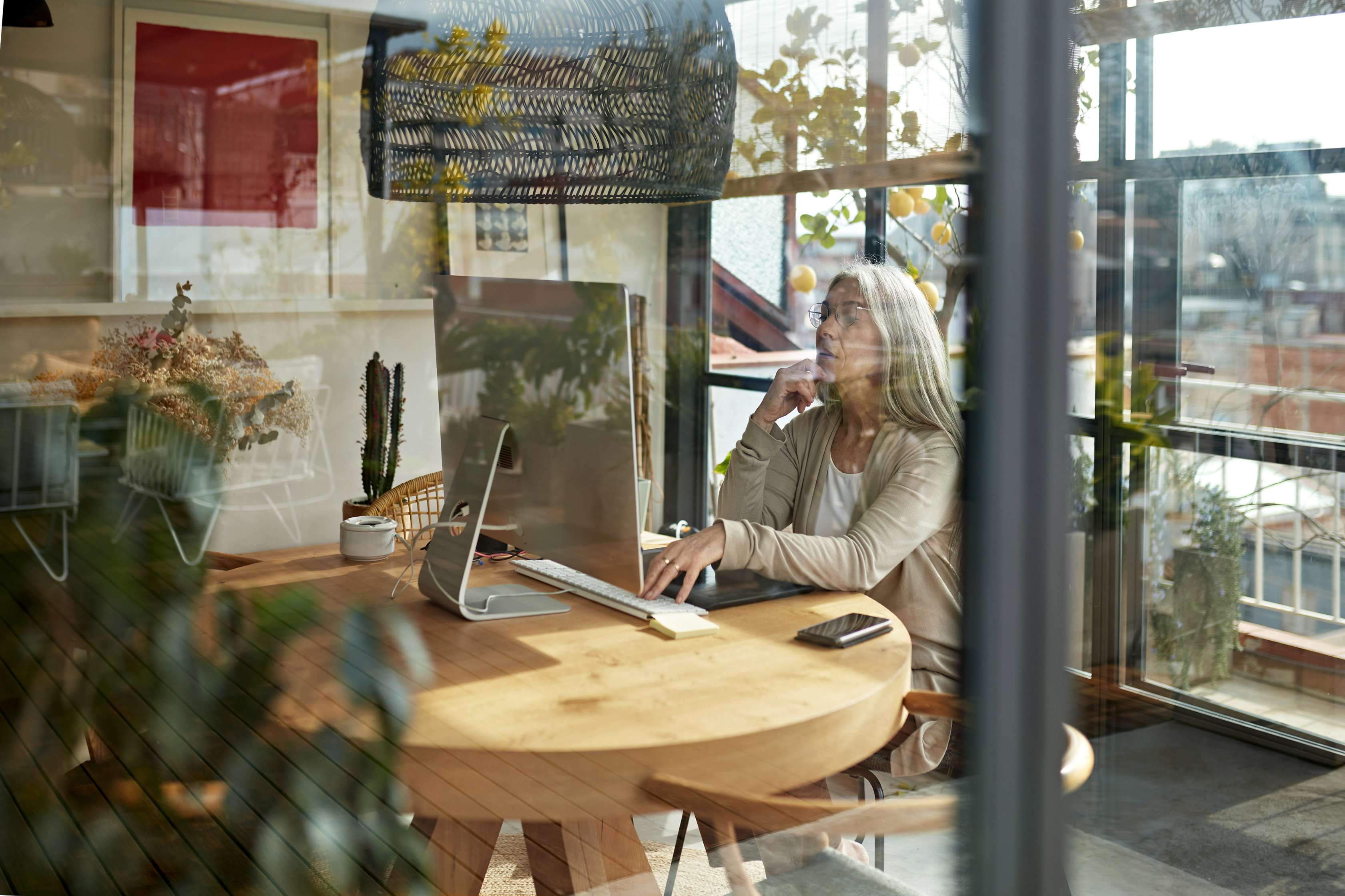 Eine Frau sitzt im Wintergarten an einem Computer