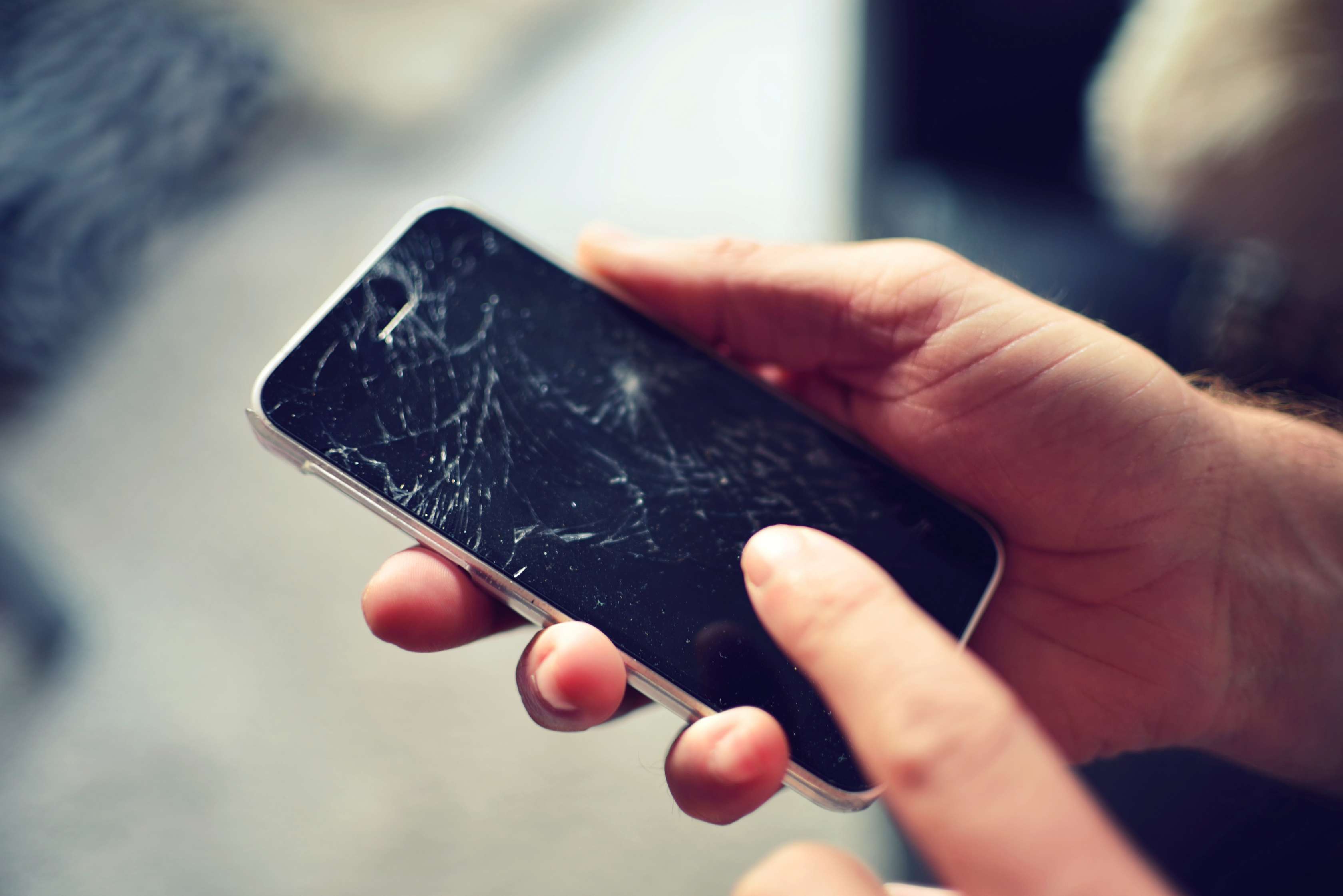 Allianz - Haftpflichtversicherung Handy: Frau hält Smartphone mit gesplittertem Display in der Hand