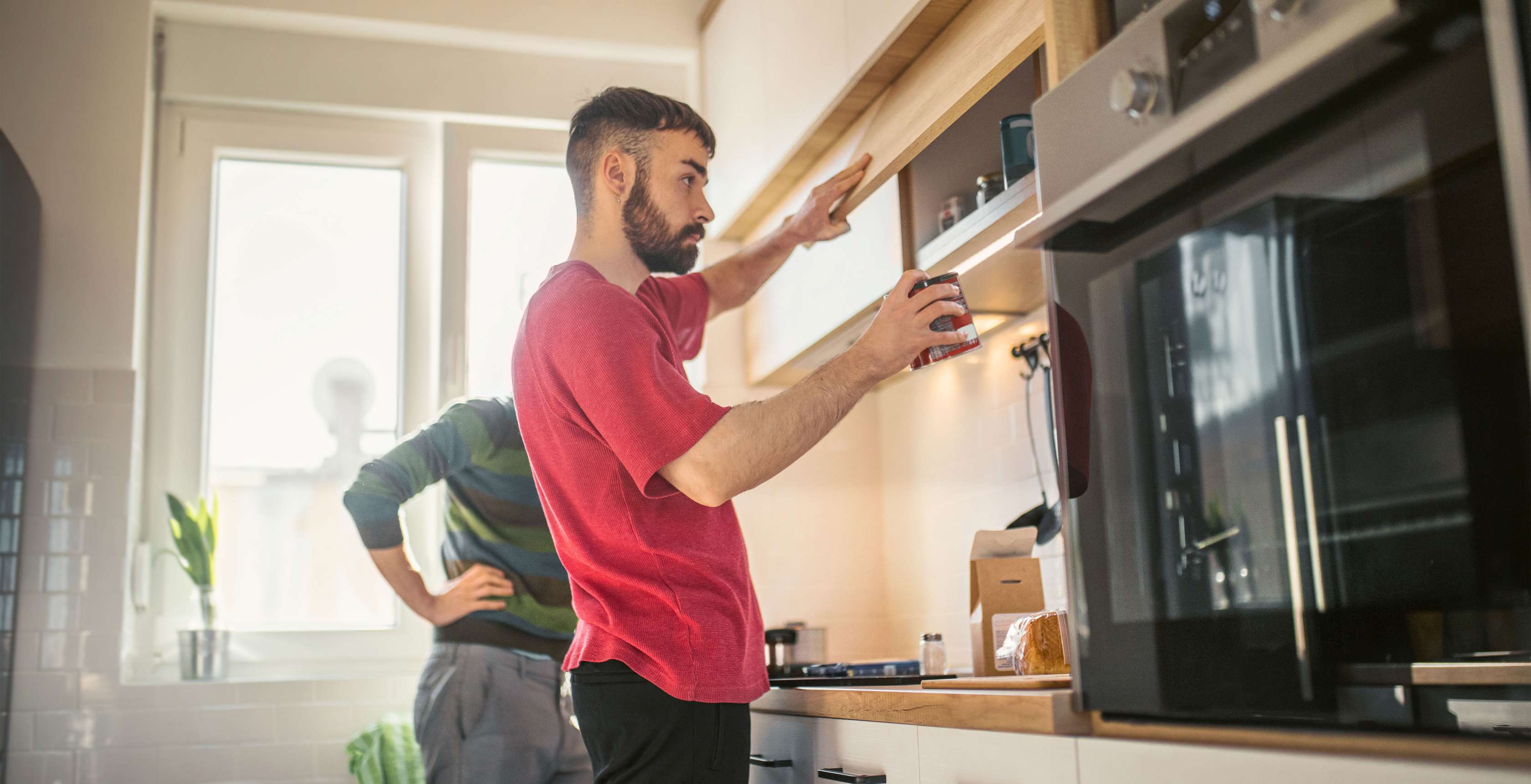 Geheimverstecke für Ihr Geld: Ein Mann stellt eine Kaffeedose in einen Küchenschrank