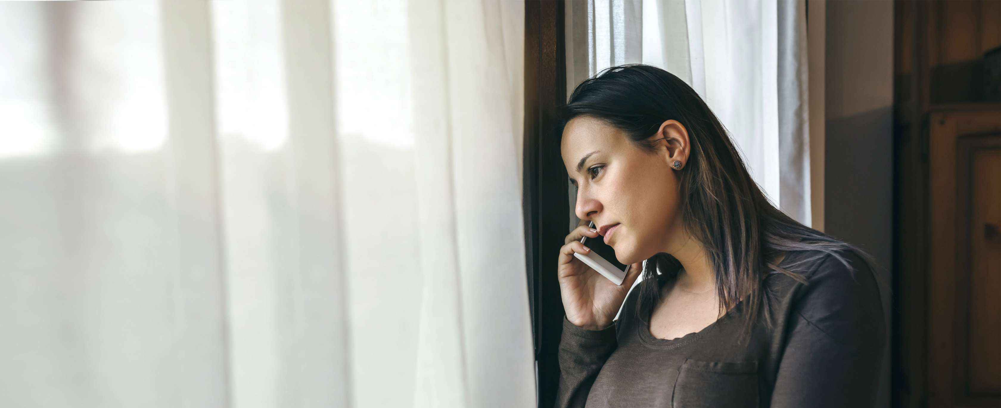 Verhalten nach Einbruch: Frau lehnt am Fenster und telefoniert