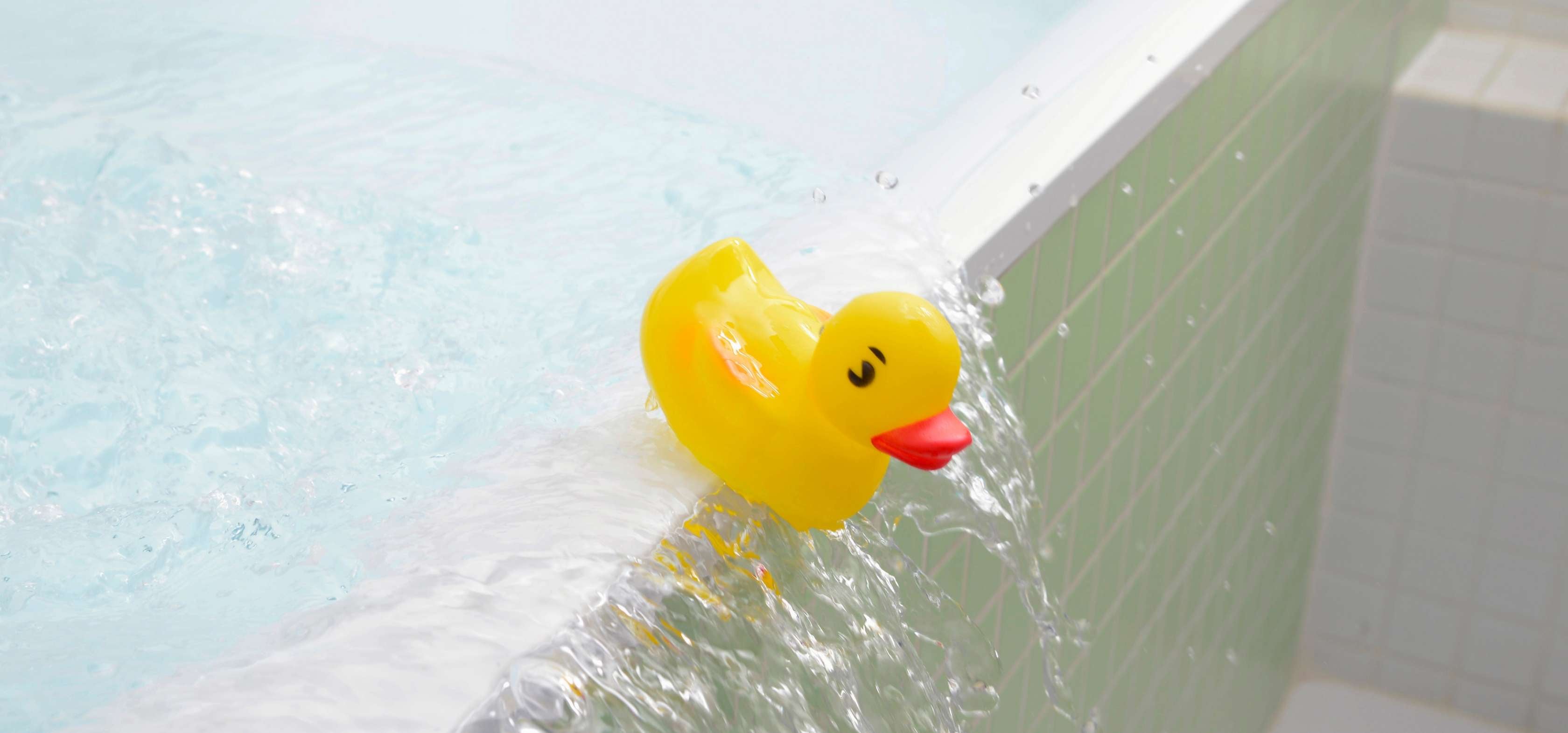 Wasserschaden: Gelbe Quietscheente schwappt mit Wasser aus überlaufender Badewanne