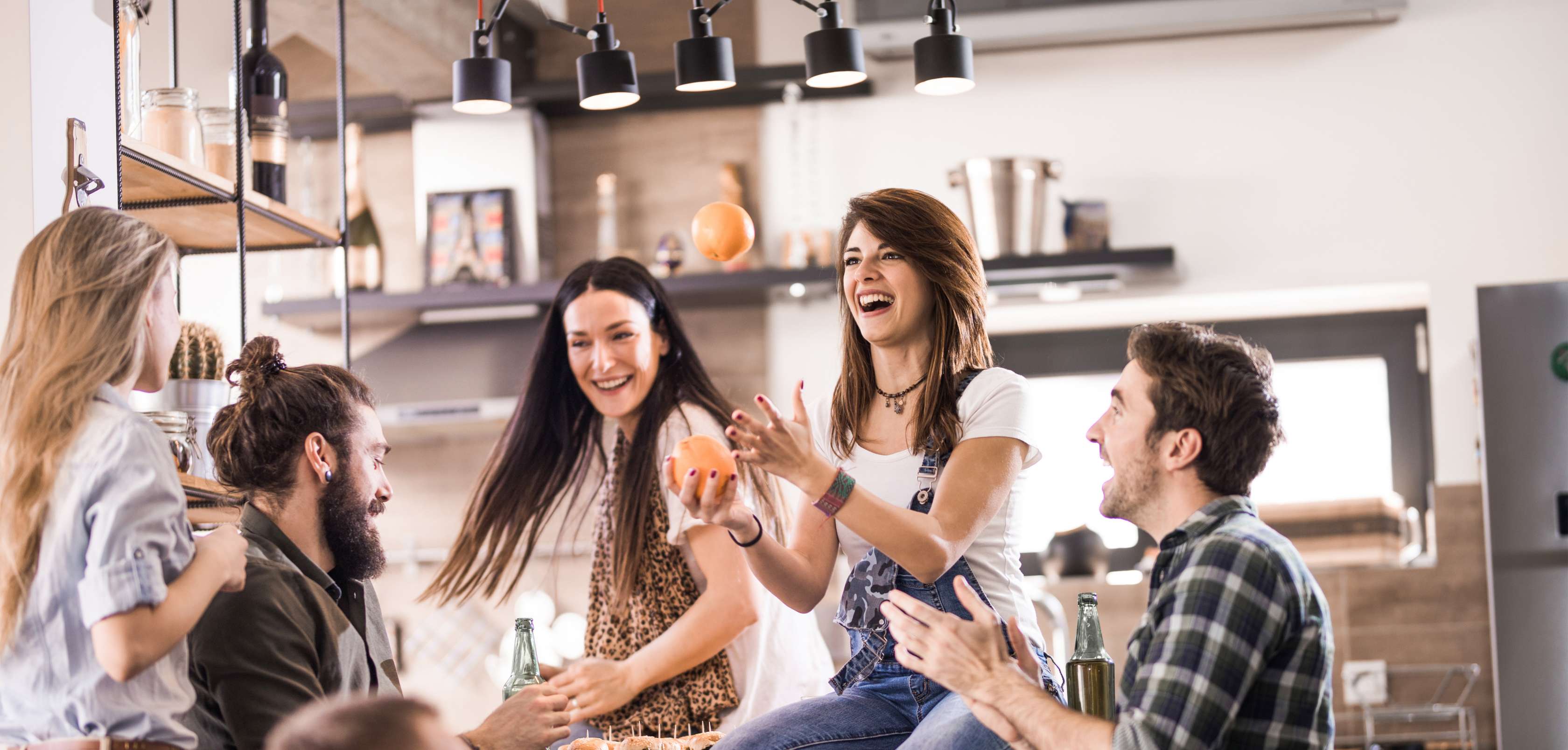 Allianz - Hausratversicherung - WG Schutz: Eine Gruppe von jungen Menschen sitzt lachend in der Küche