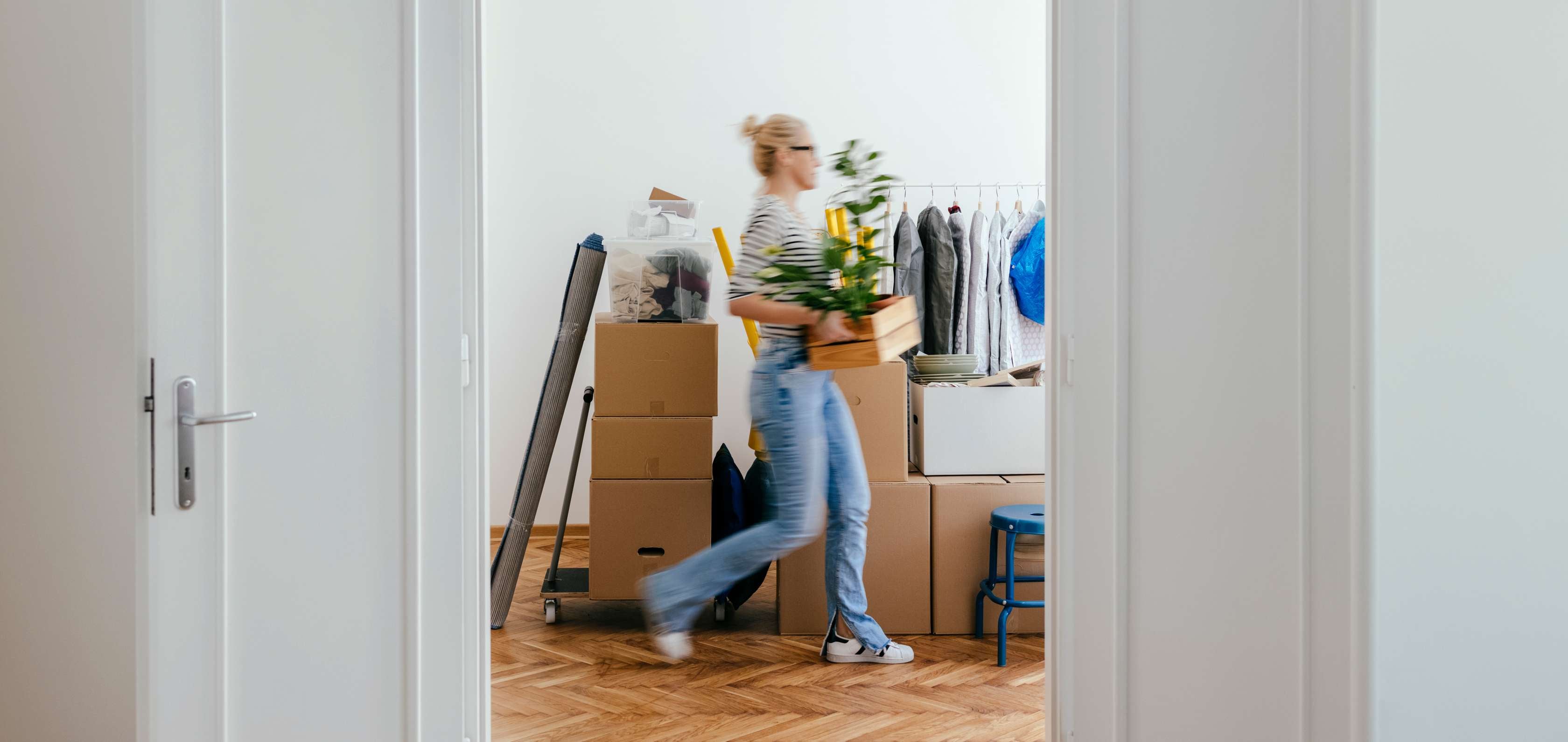 Mietkautionskonto: Eine Frau trägt Umzugskartons in eine neue Wohnung