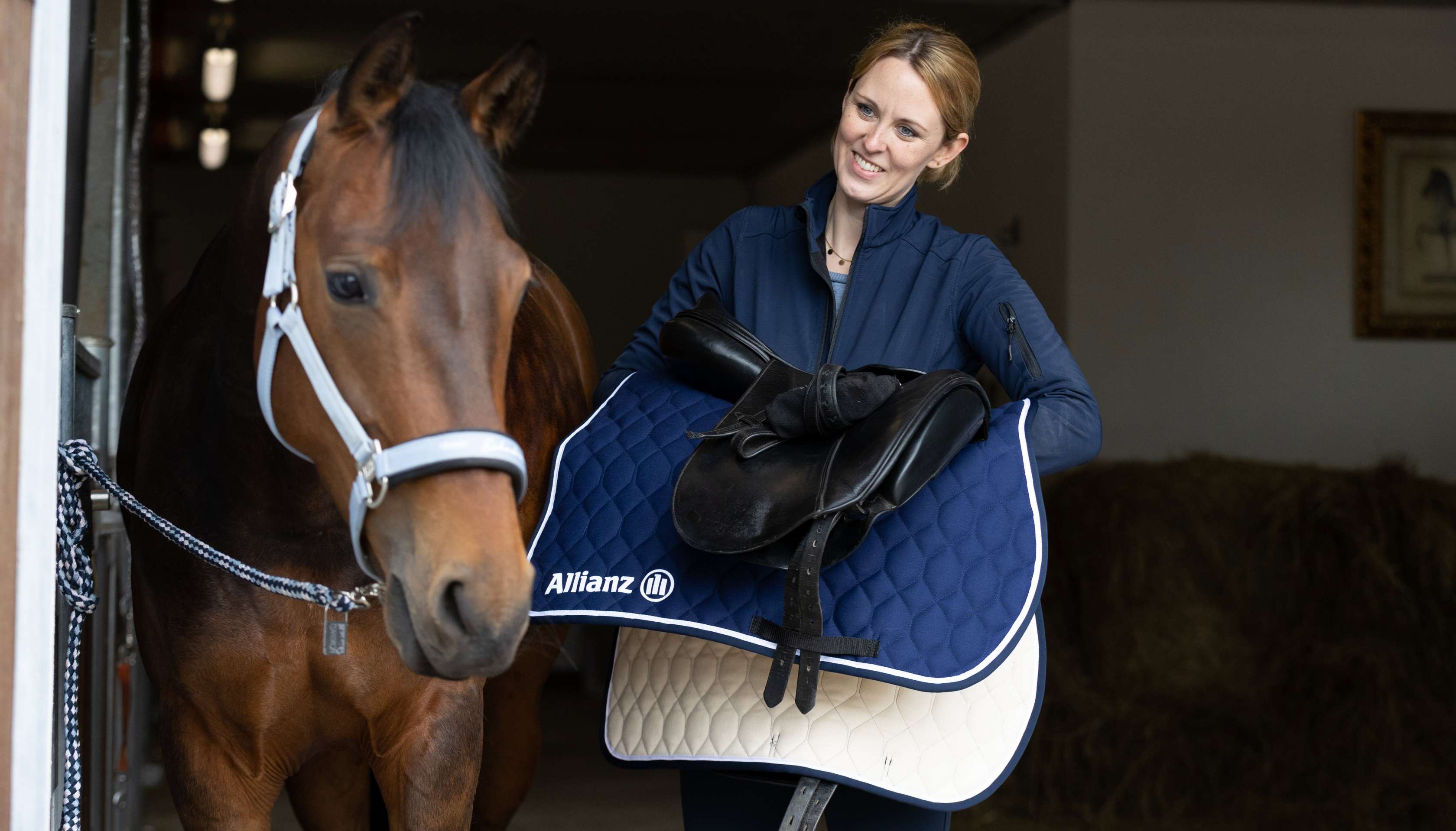 Pferdeversicherung: Eine Reiterin sattelt ihr Pferd